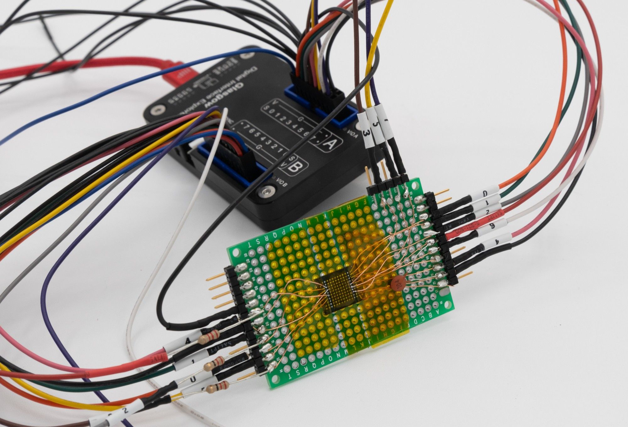 A NAND flash chip (BGA) mounted on a circuit board, with a Glasgow interface explorer in the background