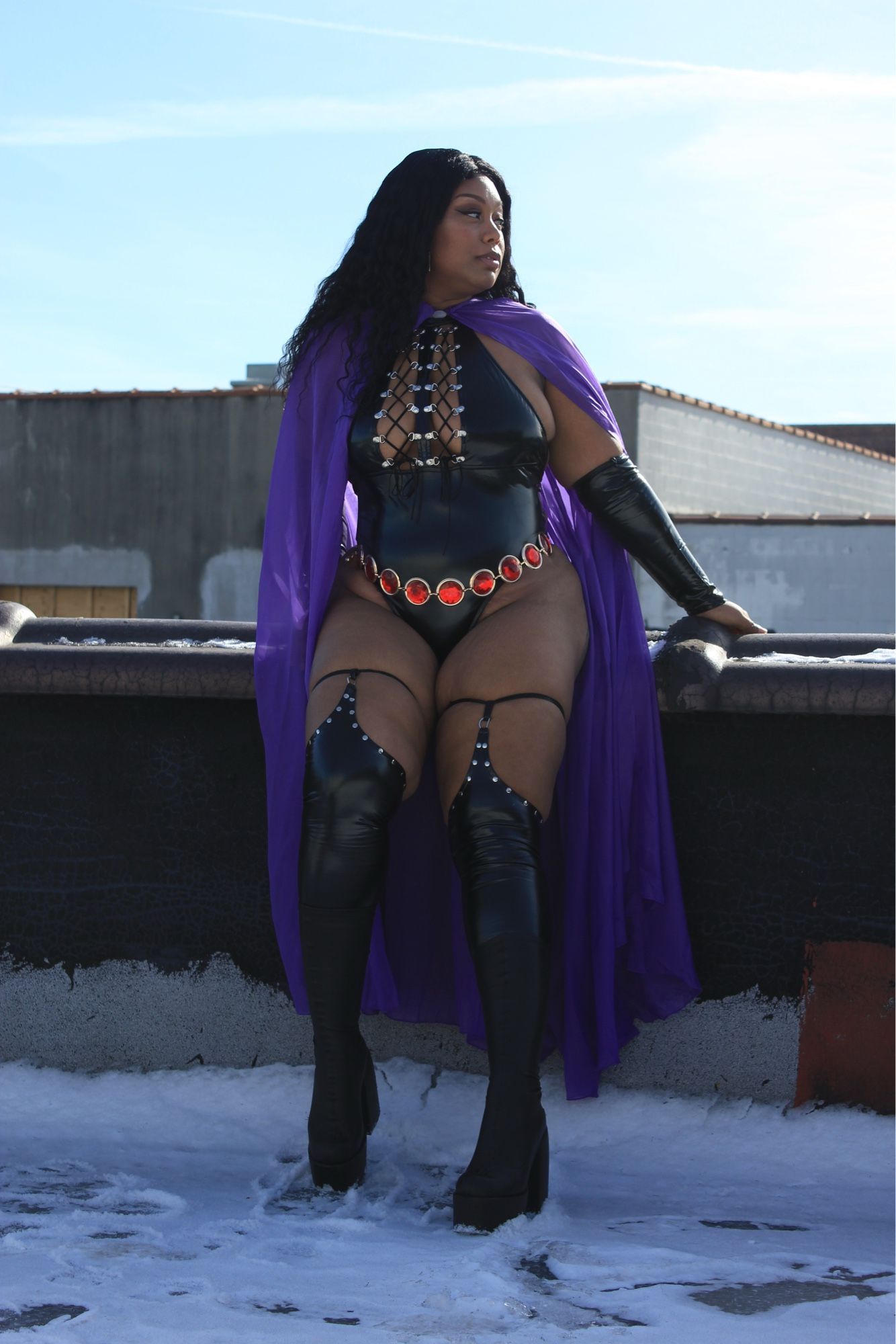 Princess sitting on a ledge, dressed as Raven from teen titans looking off into the distance