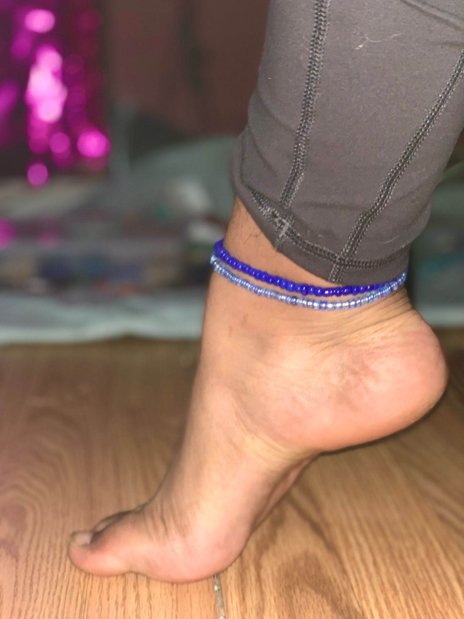 Princess feet showing the arch and 2 blue ankle bracelets on their ankle