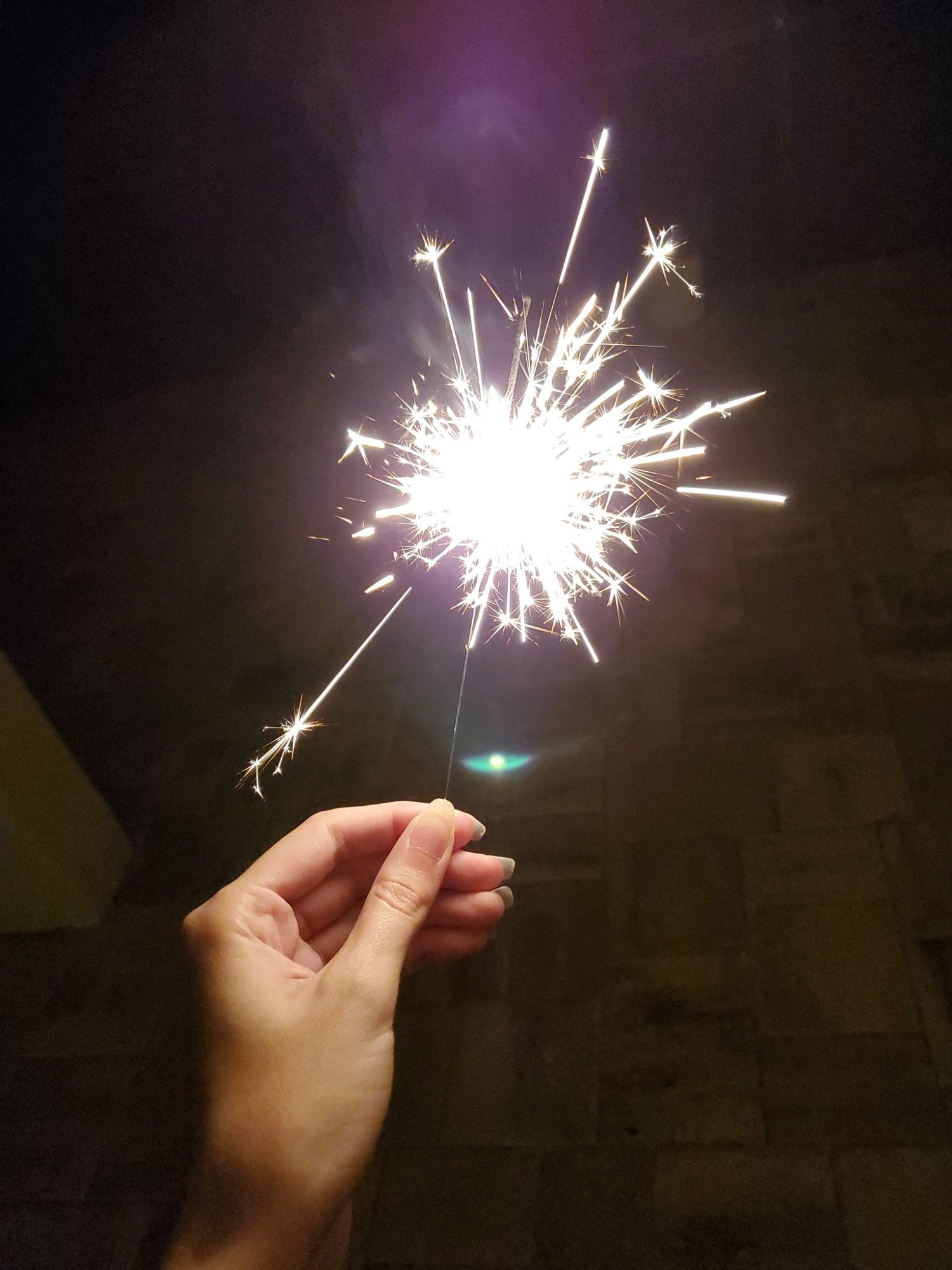 A stock photo of a hand holding a sparkler.