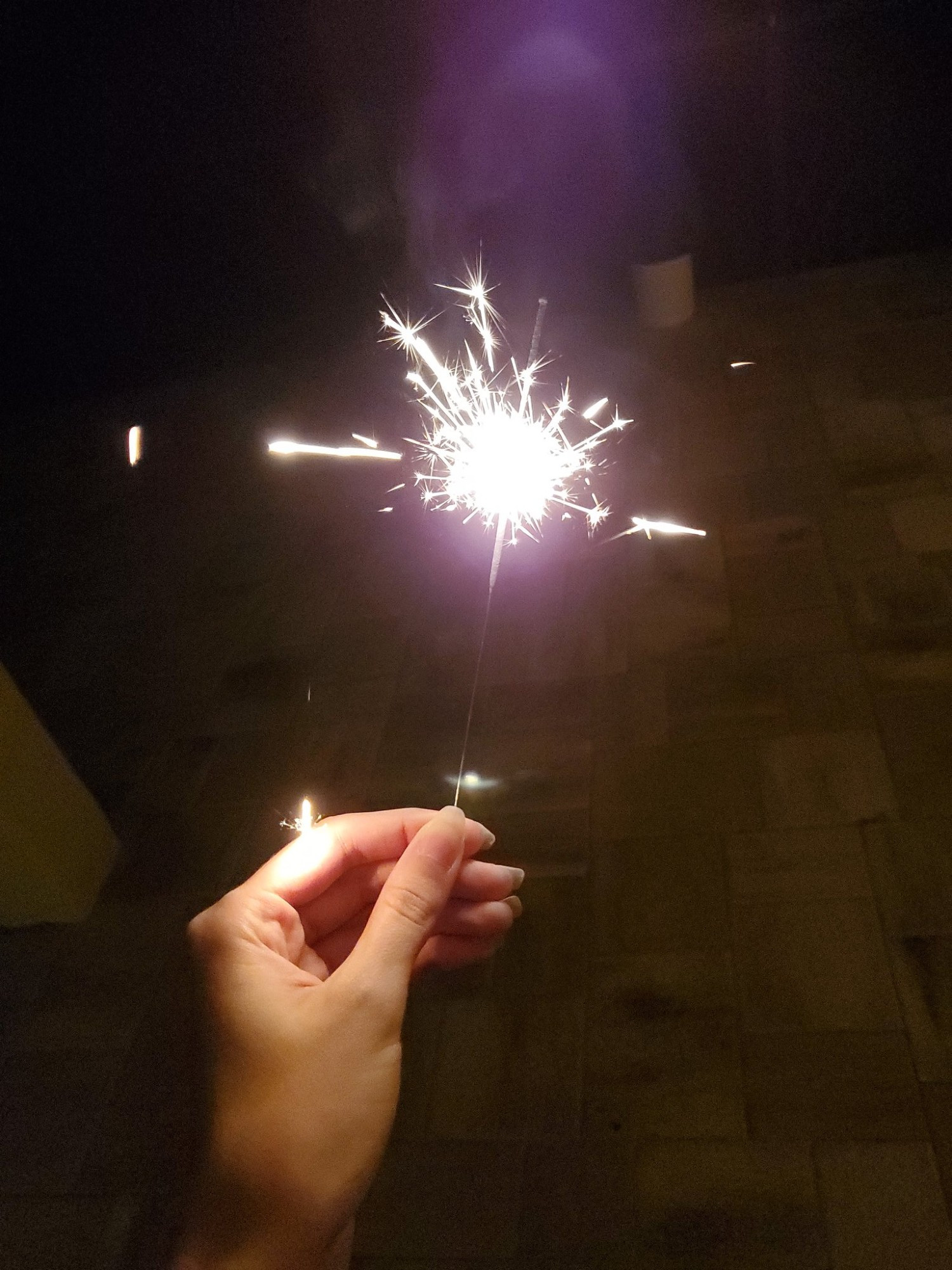 A stock photo of a hand holding a sparkler.