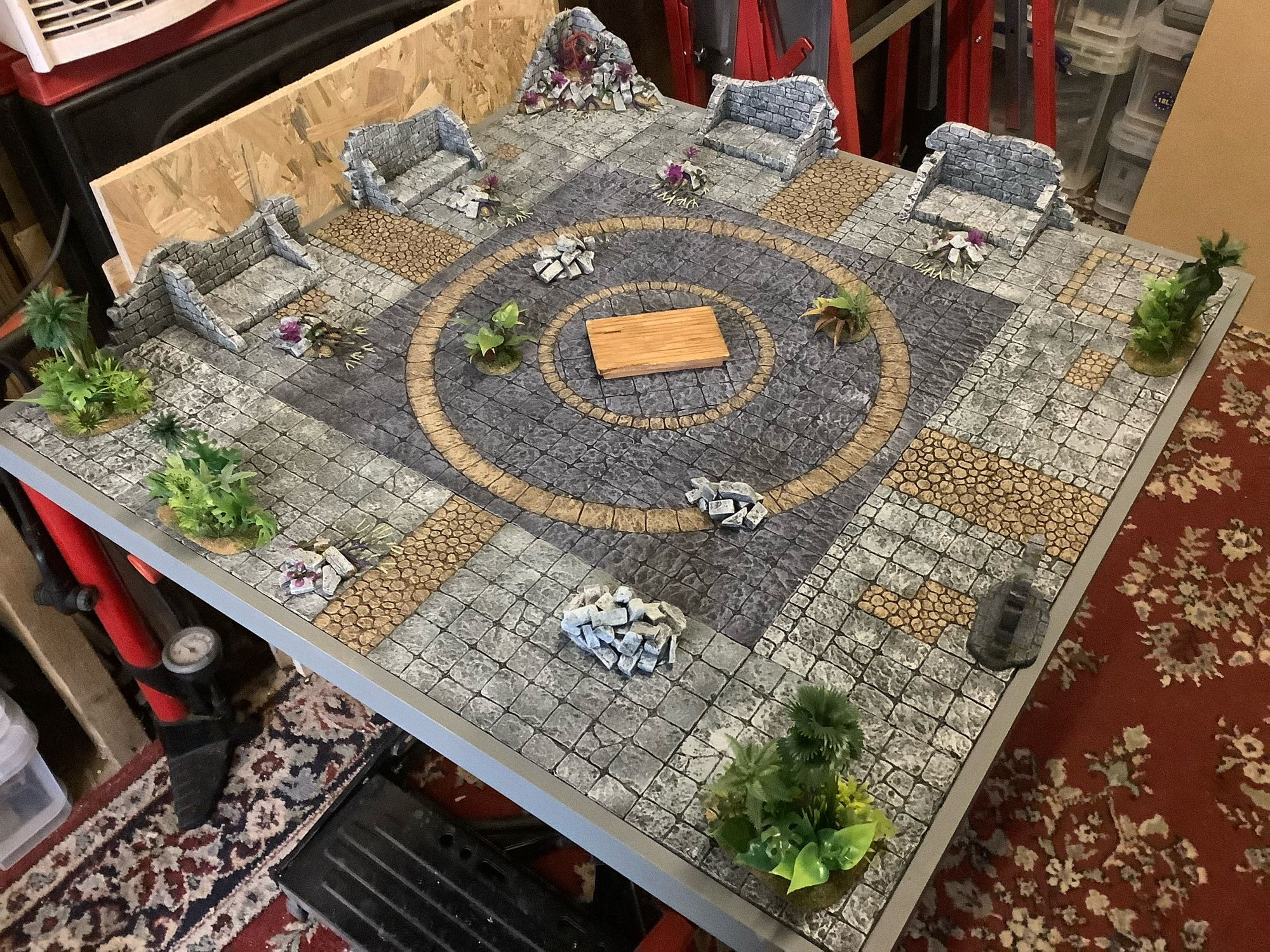 Photo of a set up for 28mm miniatures game of “Rangers of Shadowdeep”

Various shades of grey flagstone floors, with buff stone highlights and various plants and paraphernalia liberally scattered around.