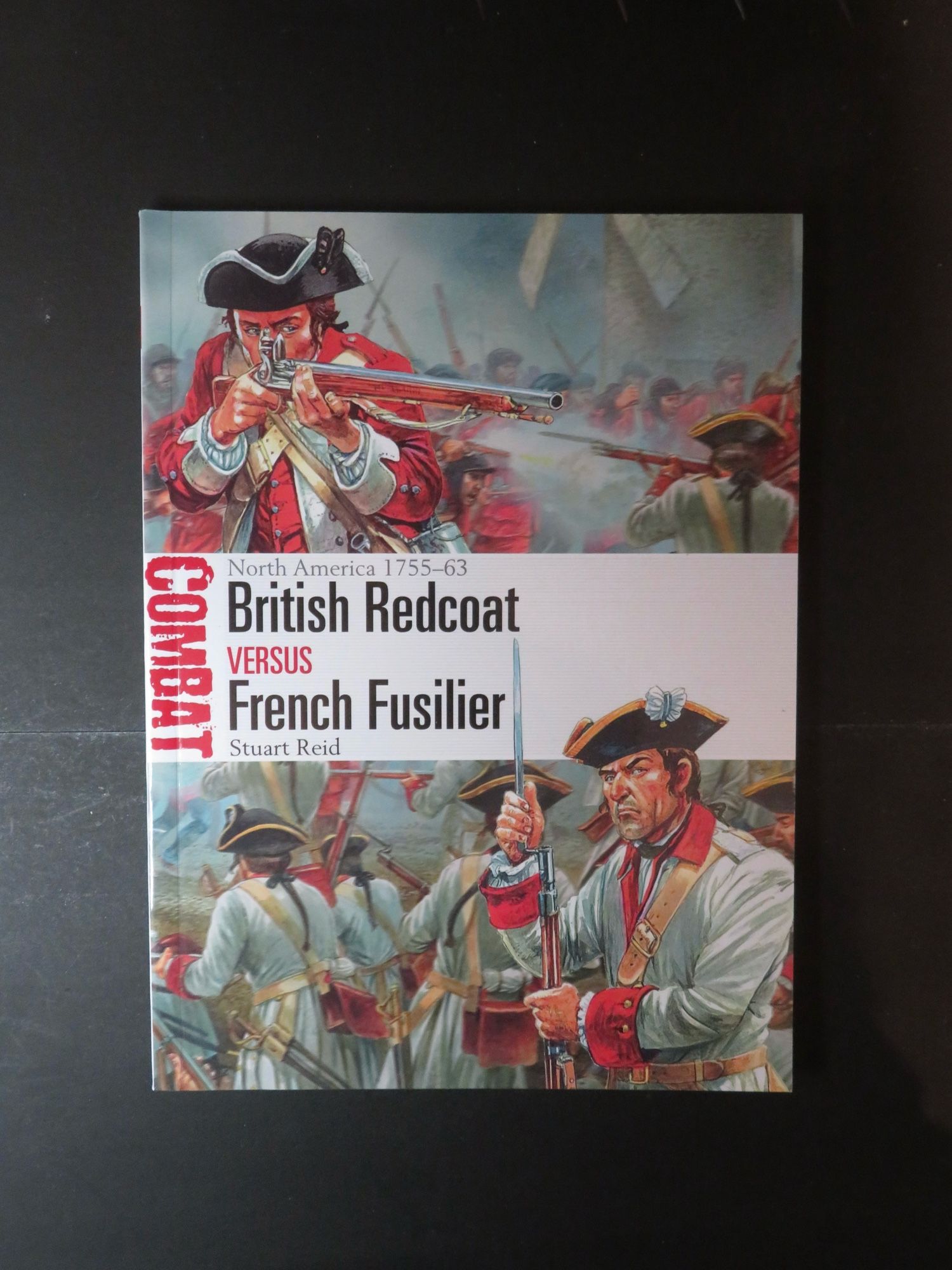 Photo of book cover on black ground. The title of the book is “Combat - British Redcoats versus French Fusilier”. It is a publication from Osprey and details the two types of soldiers and their tactics during the North American campaign of 1765 - 1763.

The cover layout has depictions of a British redcoat on the left of the picture aiming his musket to the diagonal mid-right to the upper part of the page. To the bottom of the page is a depiction of several French Fusiliers in grey coats with red collars , cuffs and waistcoats loading and firing; one looks out from the cover at the viewer. The two pictures are split horizontally by the tile of the book which is mostly black lettering on a white band.