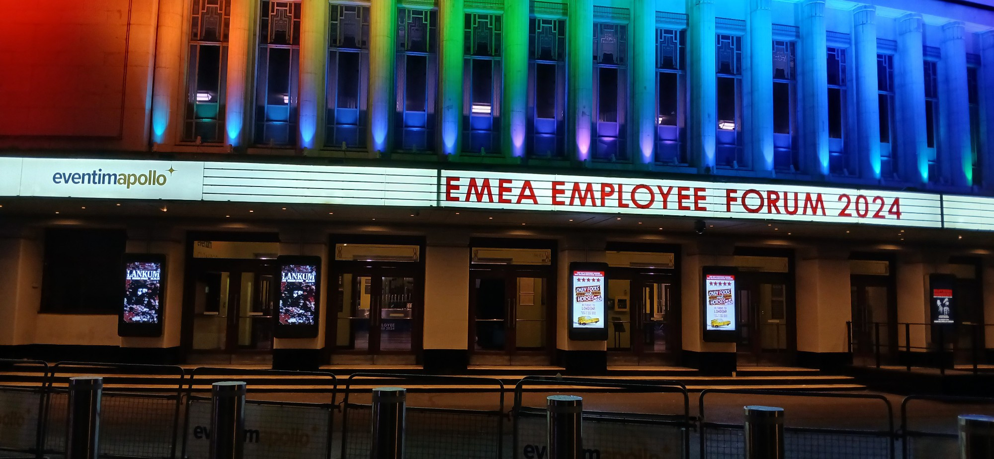 Marquee at the Eventim Apollo reading "EMEA Employee Forum 2024." The Eventim Apollo is a 5000 seat Art Deco theatre in London, shown in this photo at night, with columns above the marquee lit in different colours.