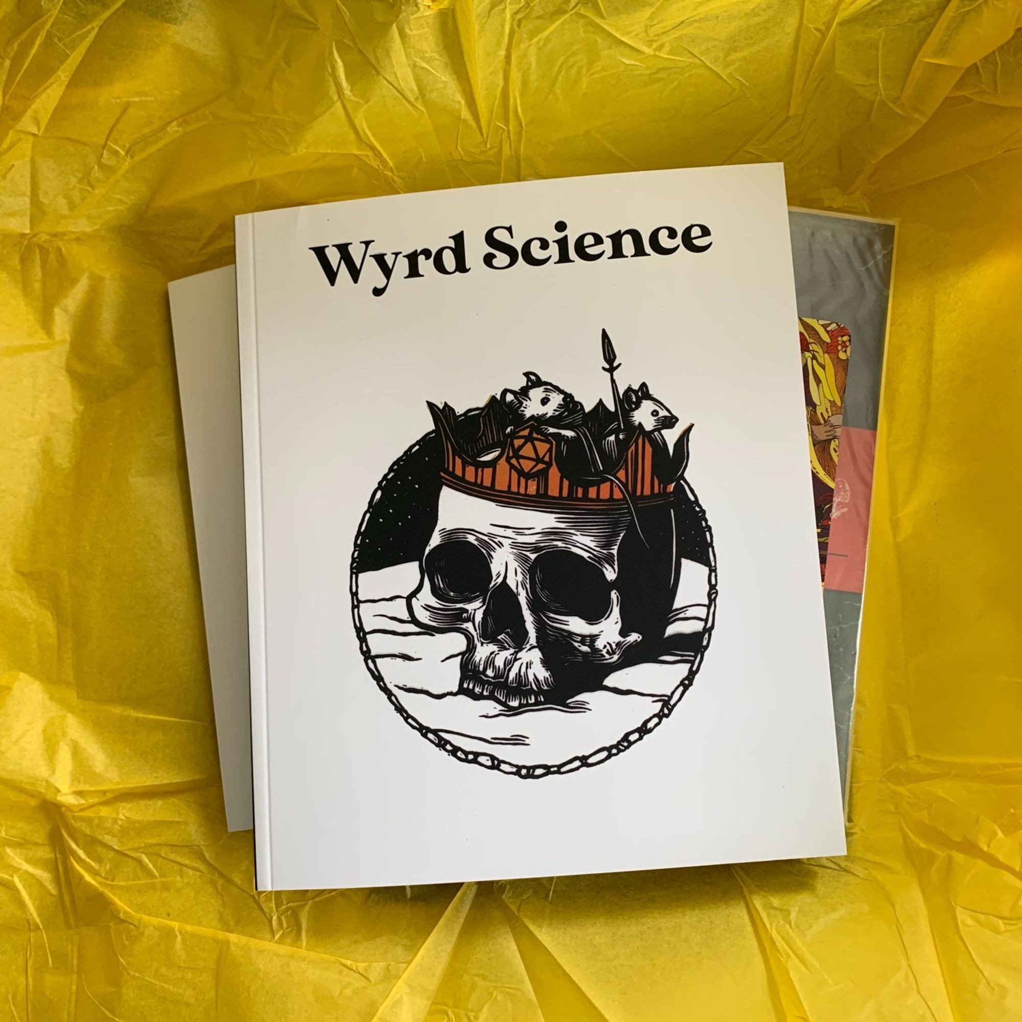 A copy of Wyrd Science issue 6, sat on yellow tissue paper.