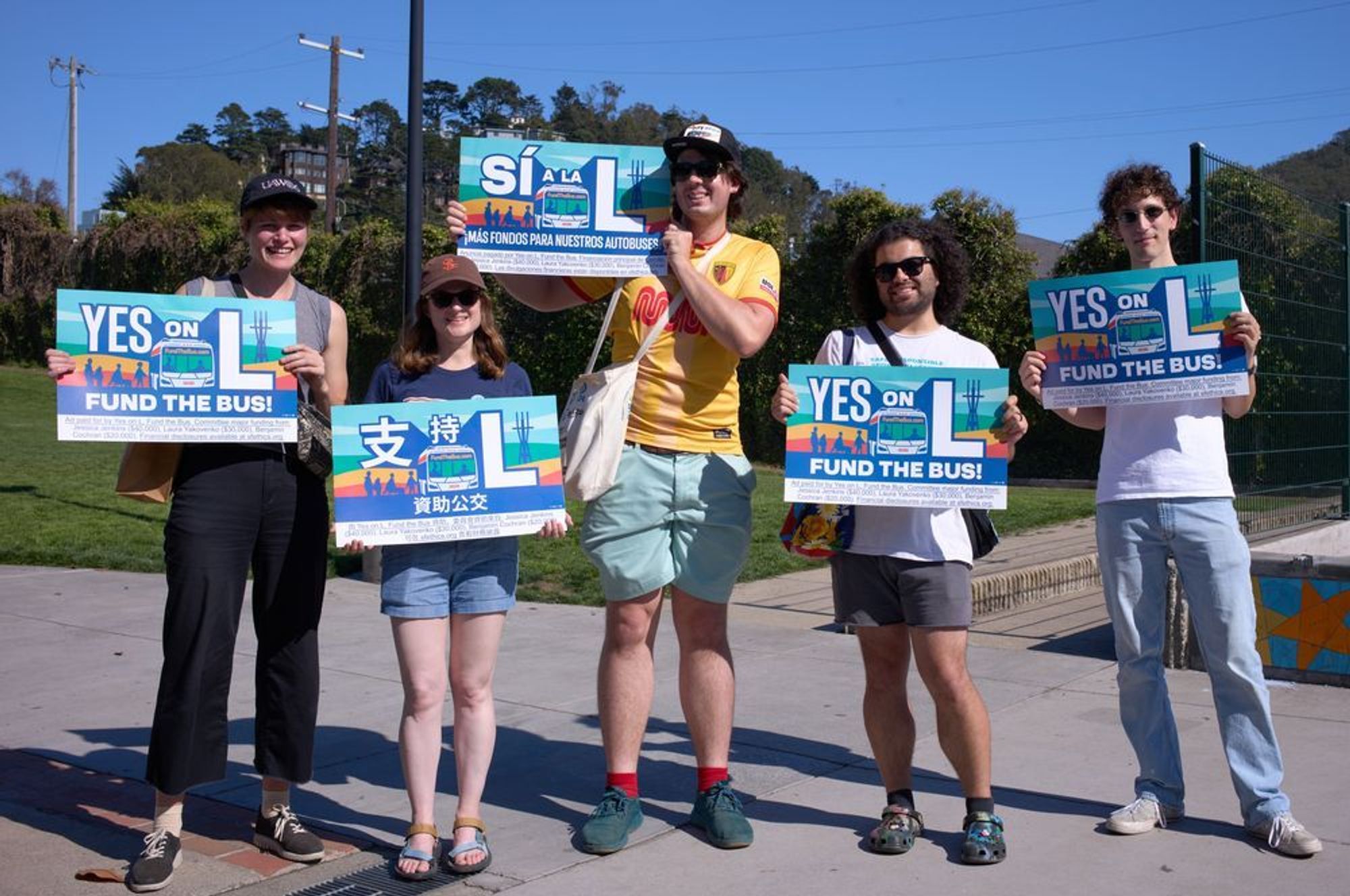 5 volunteers holding Yes on L window signs in the sun