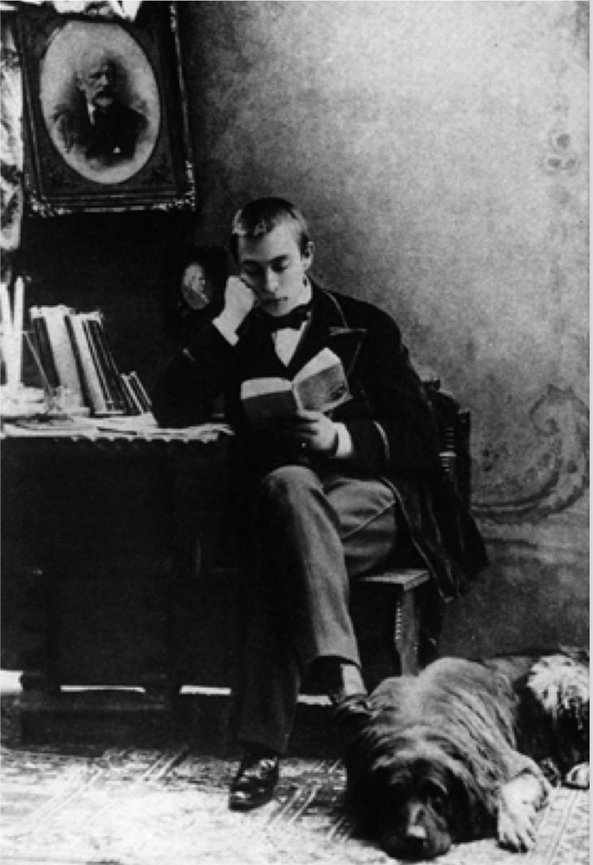 Der junge R. In seine Lektüre vertieft, zu seinen Füßen ein großer Hund.