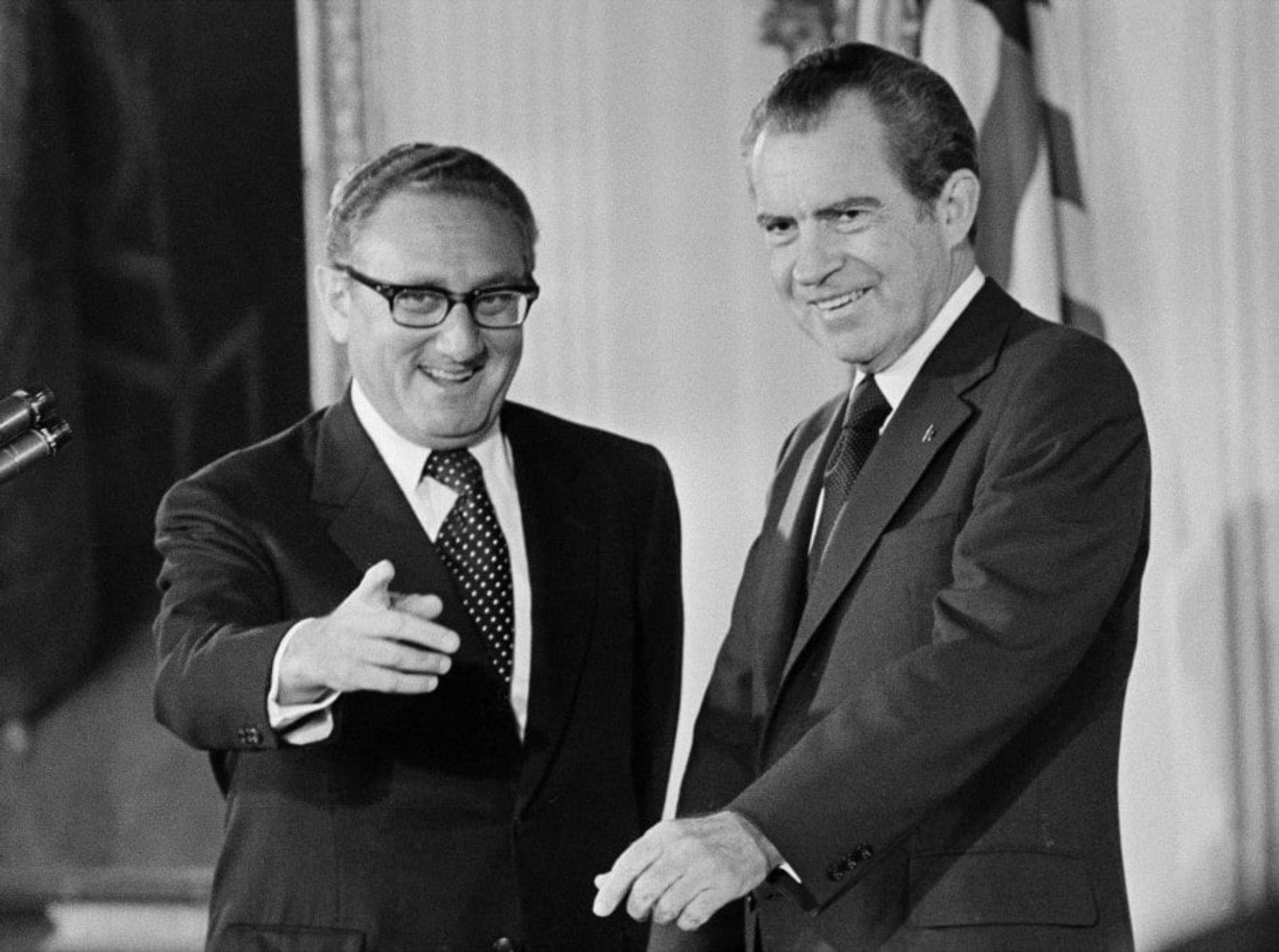 Henry Kissinger and Richard Nixon conspire over who can reach the most villainous accomplishments