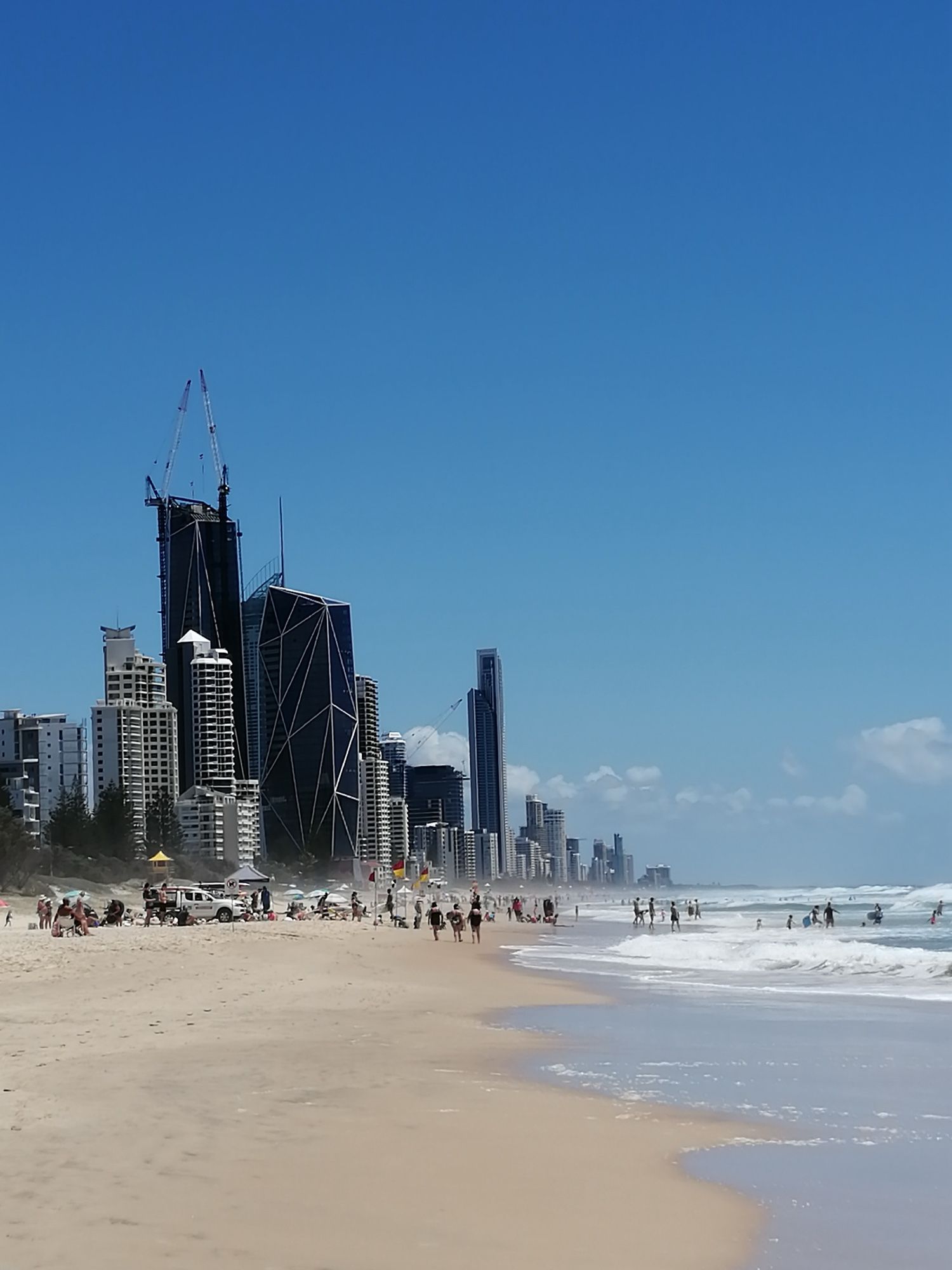 Foto zeigt die Skyline von Broadbeach, Gold Coast, Queensland, Australien, die bis an den Strand reicht. Rechts das Meer. Blauer Himmel.