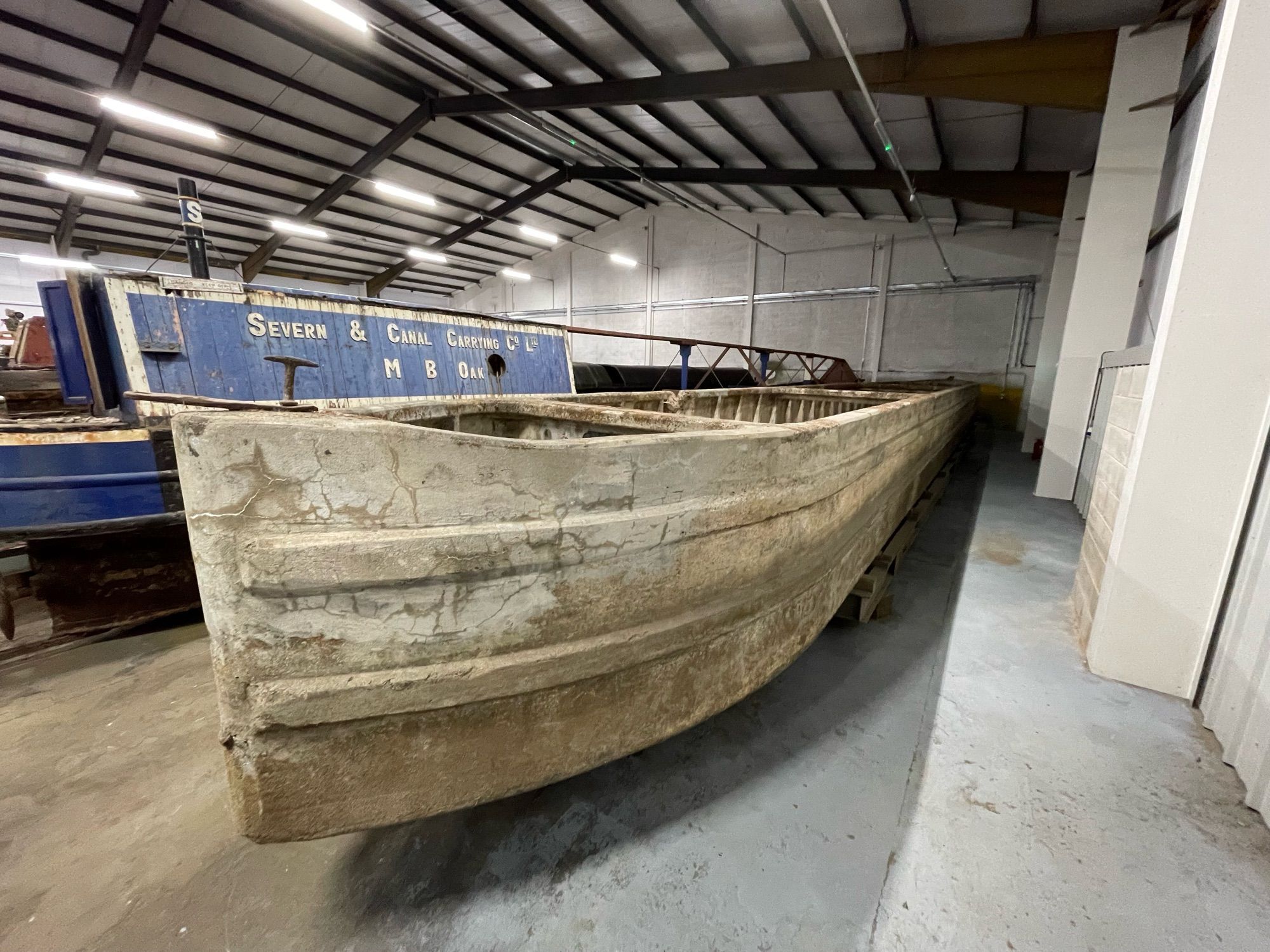 A concrete canal boat, stored in a large building.