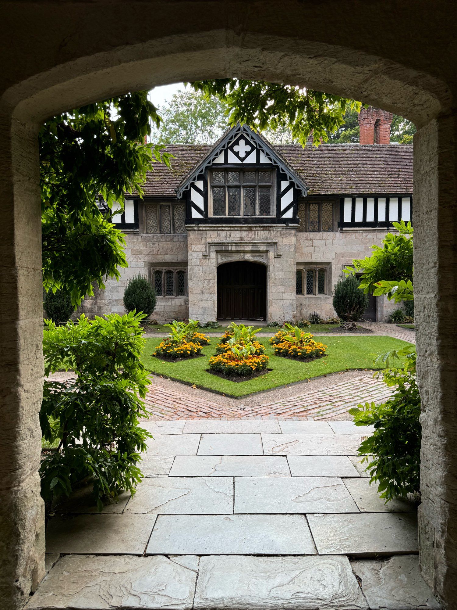 View through a stone arch into a formal courtyard garden.