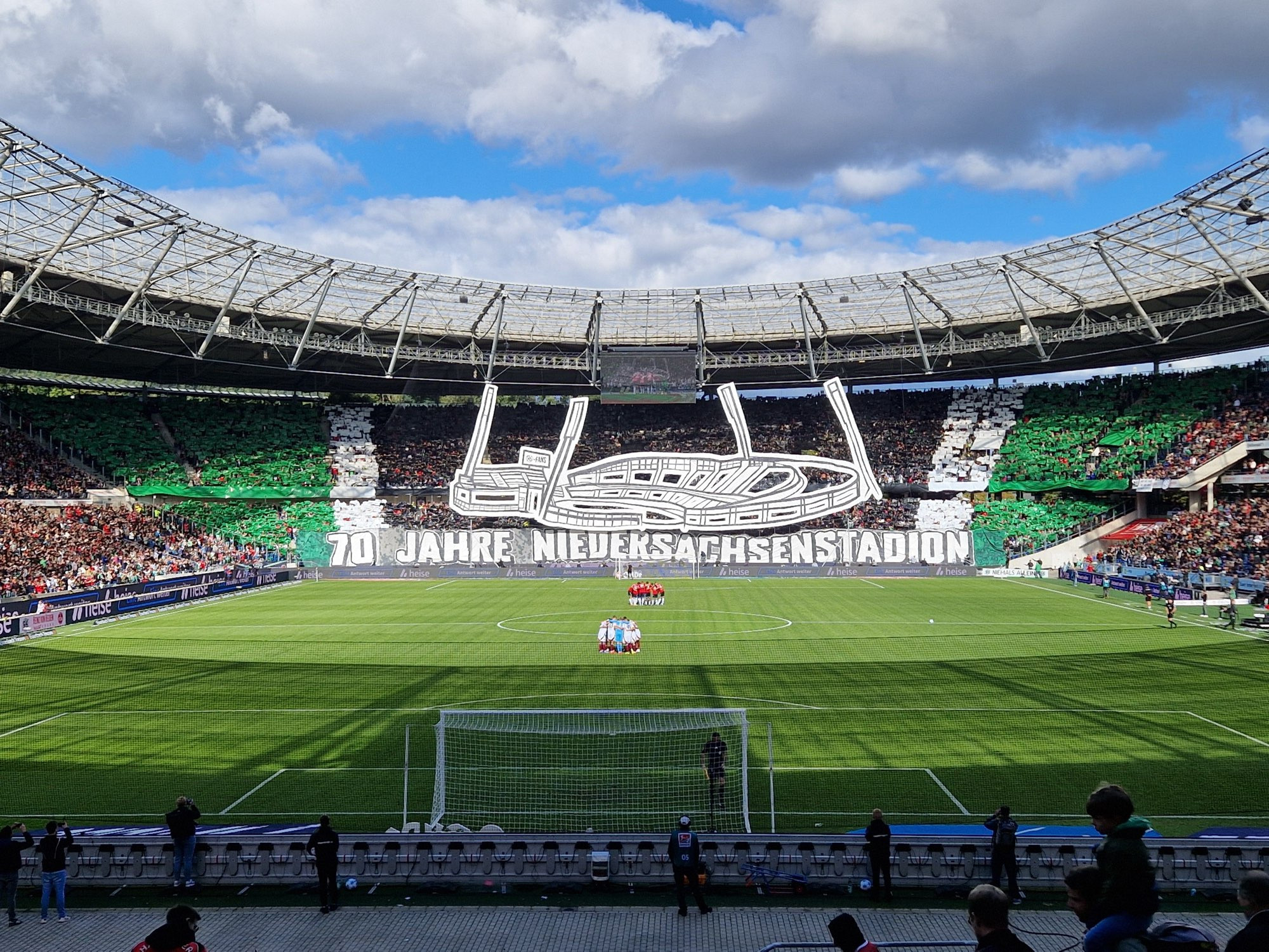 Fanchoreo mit Silhouette des Stadions in früherem Zustand mit Flutlichtmasten und Spruchband „70 Jahre Niedersachsenstadion“