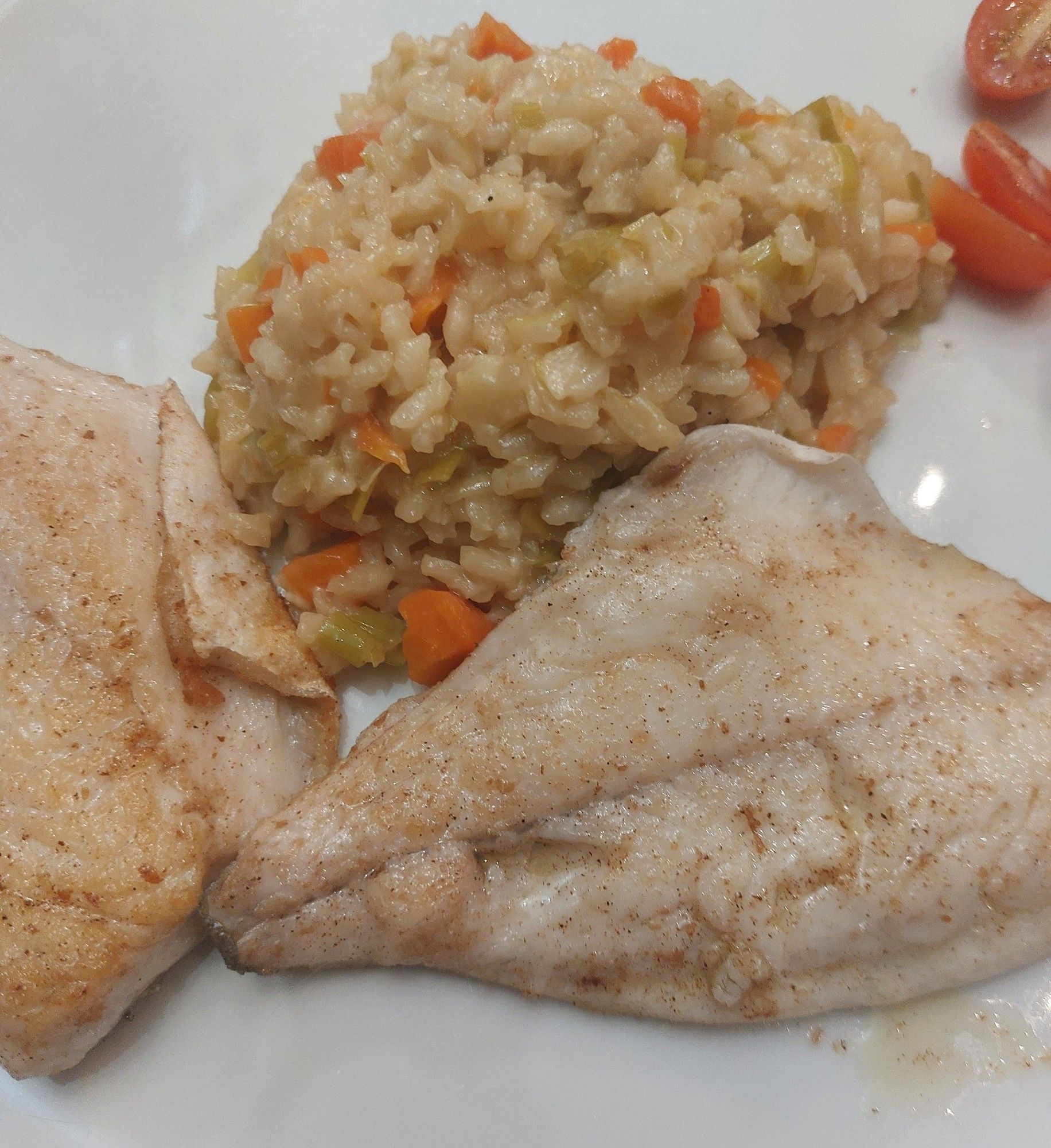 Weißer Teller, Risotto, Wurzelgemüse oben, darunter zwei Filets von der Dorade