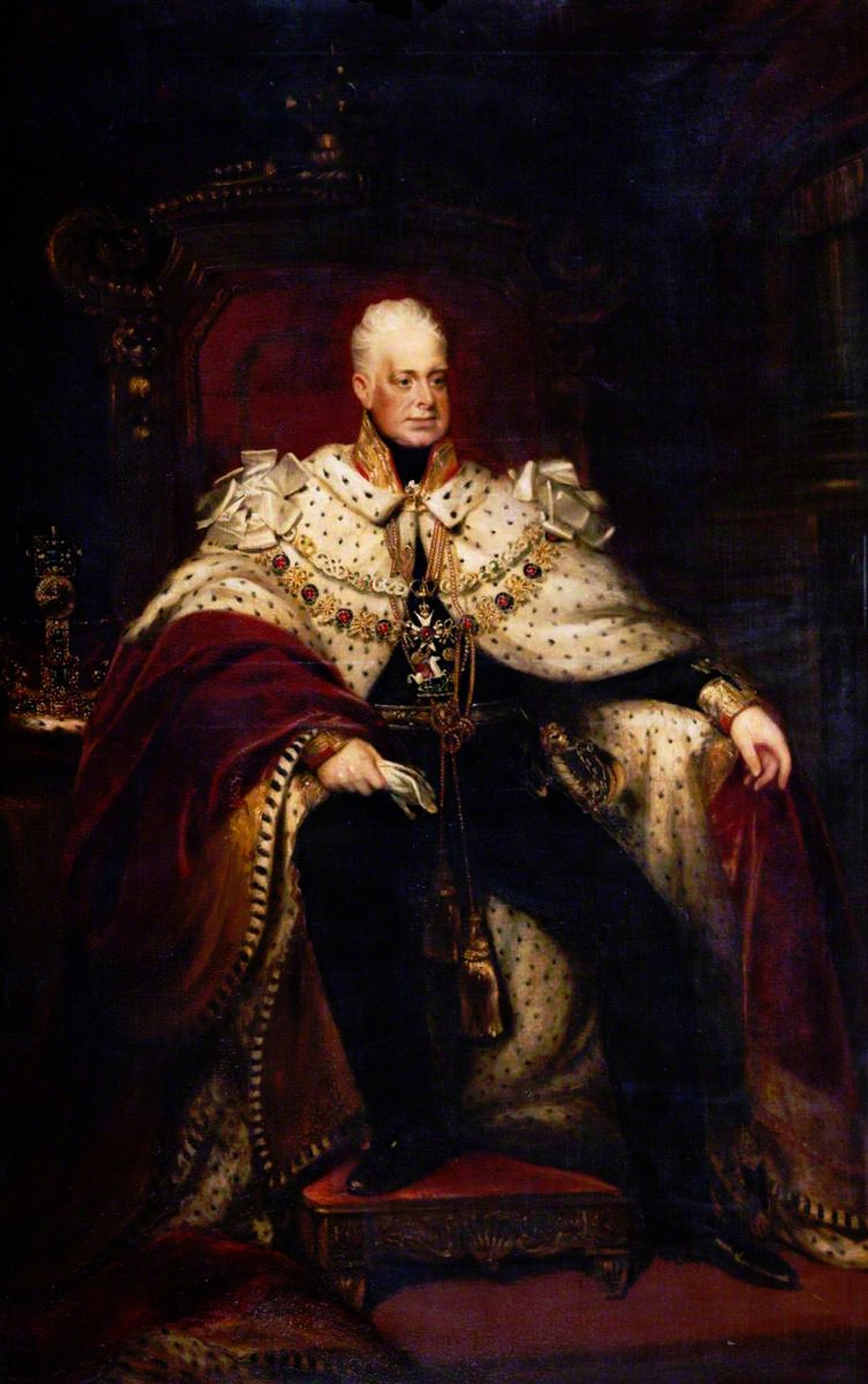 Portrait of an older man with short white hair, sitting on a throne with one foot on a footstool, wearing an elaborate cloak of ermine and deep red velvet over a dark uniform. He has several ceremonial gold chains.