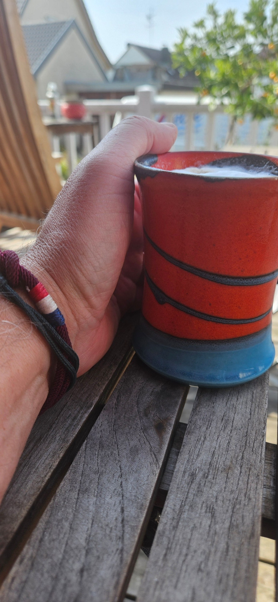 Hand mit Kaffee auf der Terrasse
