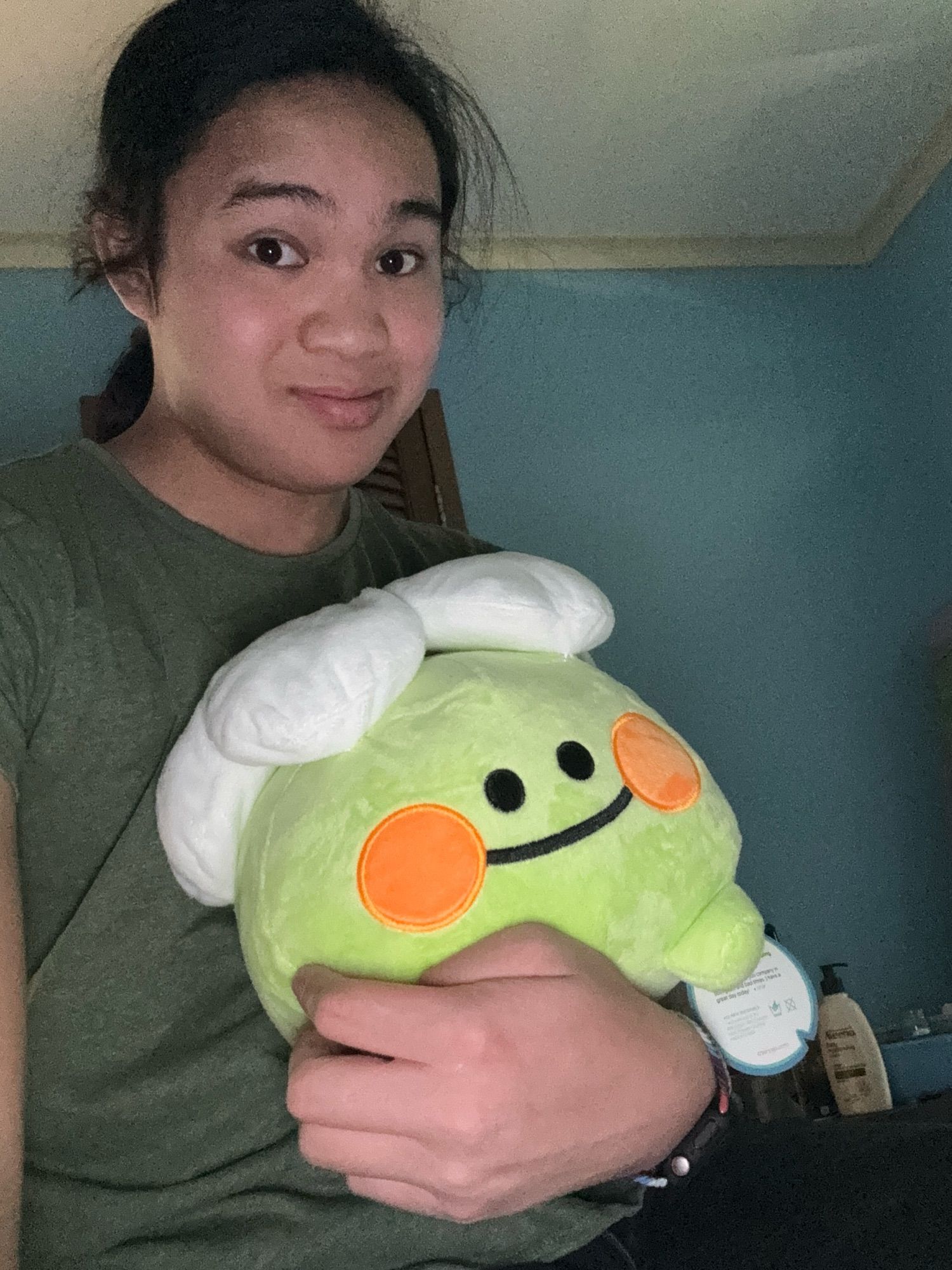 Hyla with a Froggert plush resting on their arm.