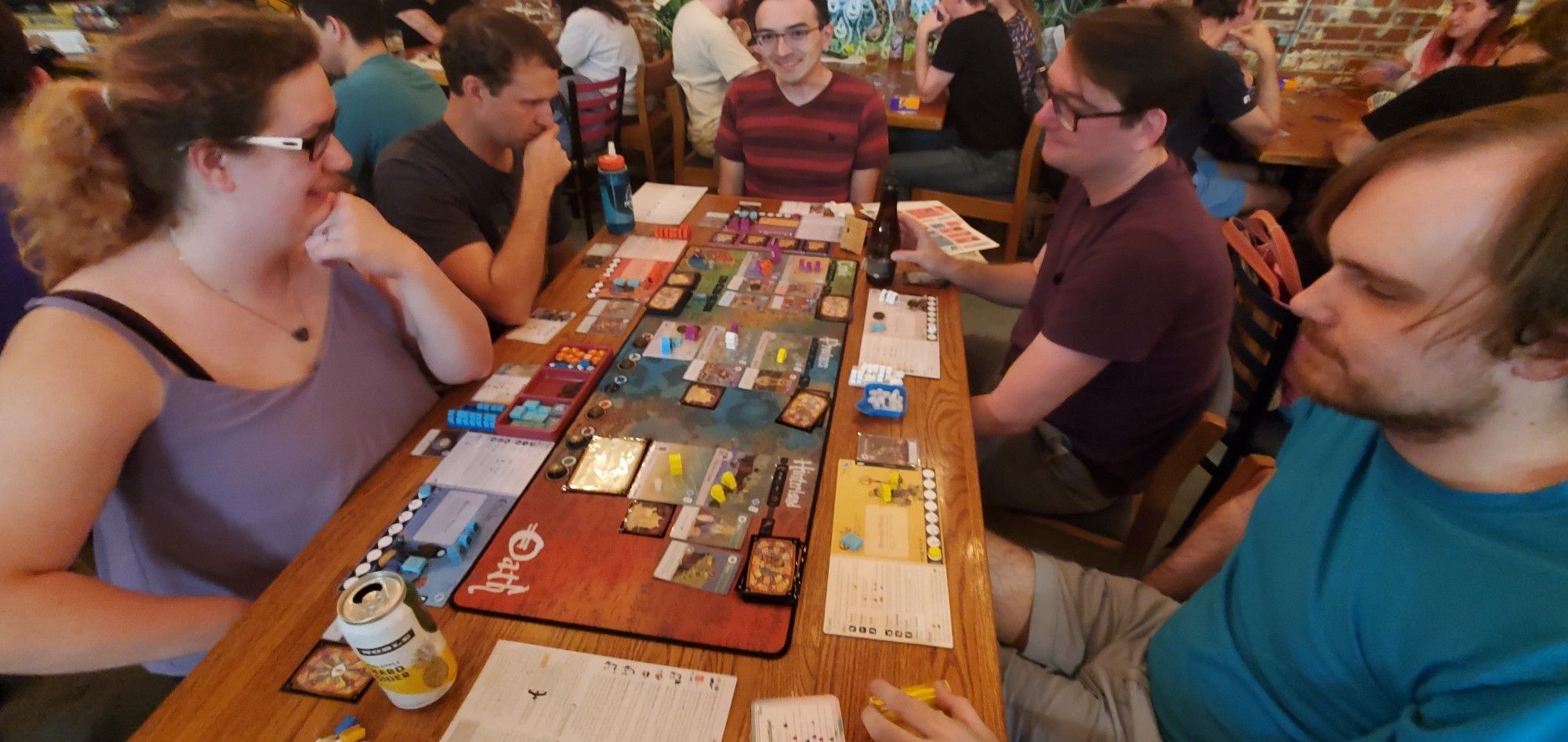 The board game Oath being played in a wode shot showing crowded players and other tables