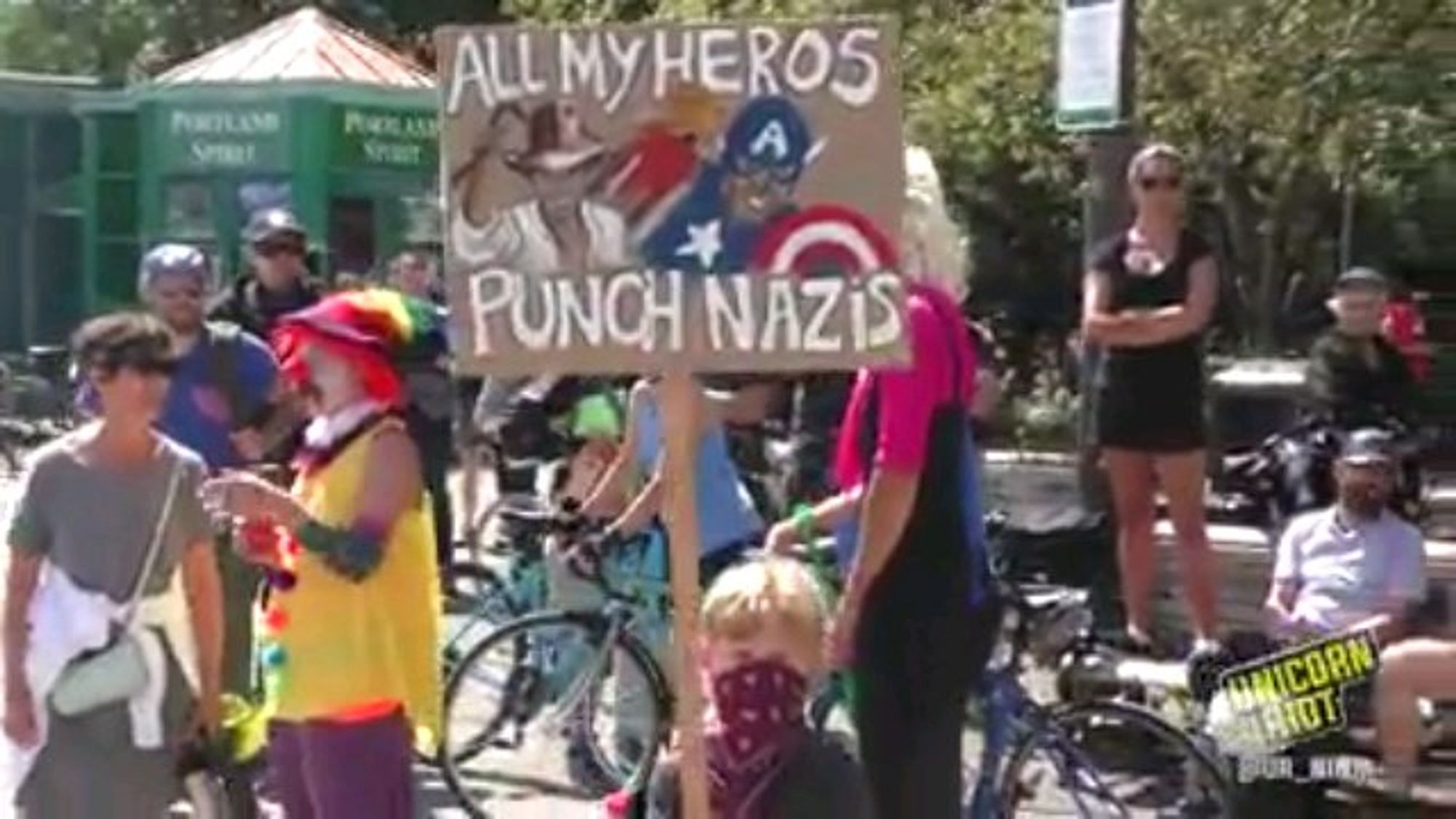 Ein mit Tuch vermummtes Kind hält ein Schild:
darauf sind Indiana Jones und Captain America gemalt und der Text: "All my heroes punch nazis"