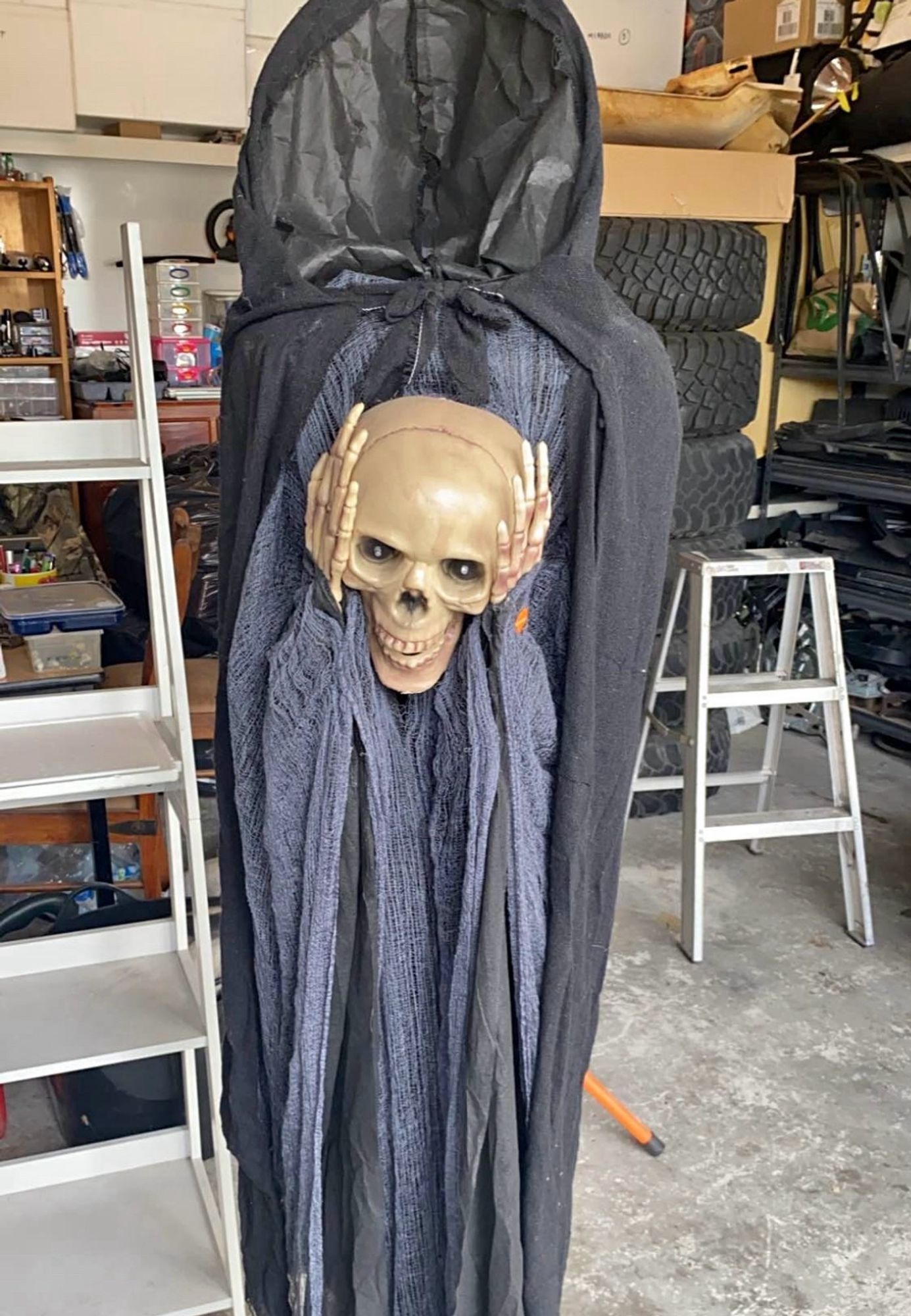 A skeleton in a black robe holding it’s skull in it’s hands