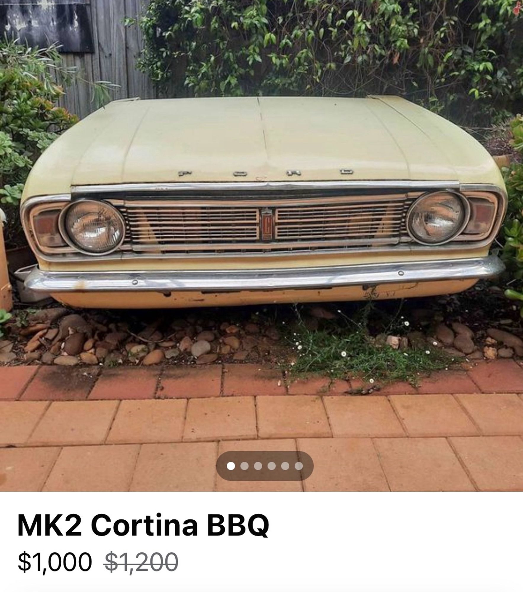 The front end of an old Ford Cortina that has been neatly sawn off the body of the car – lifting the bonnet reveals a BBQ where the motor should be