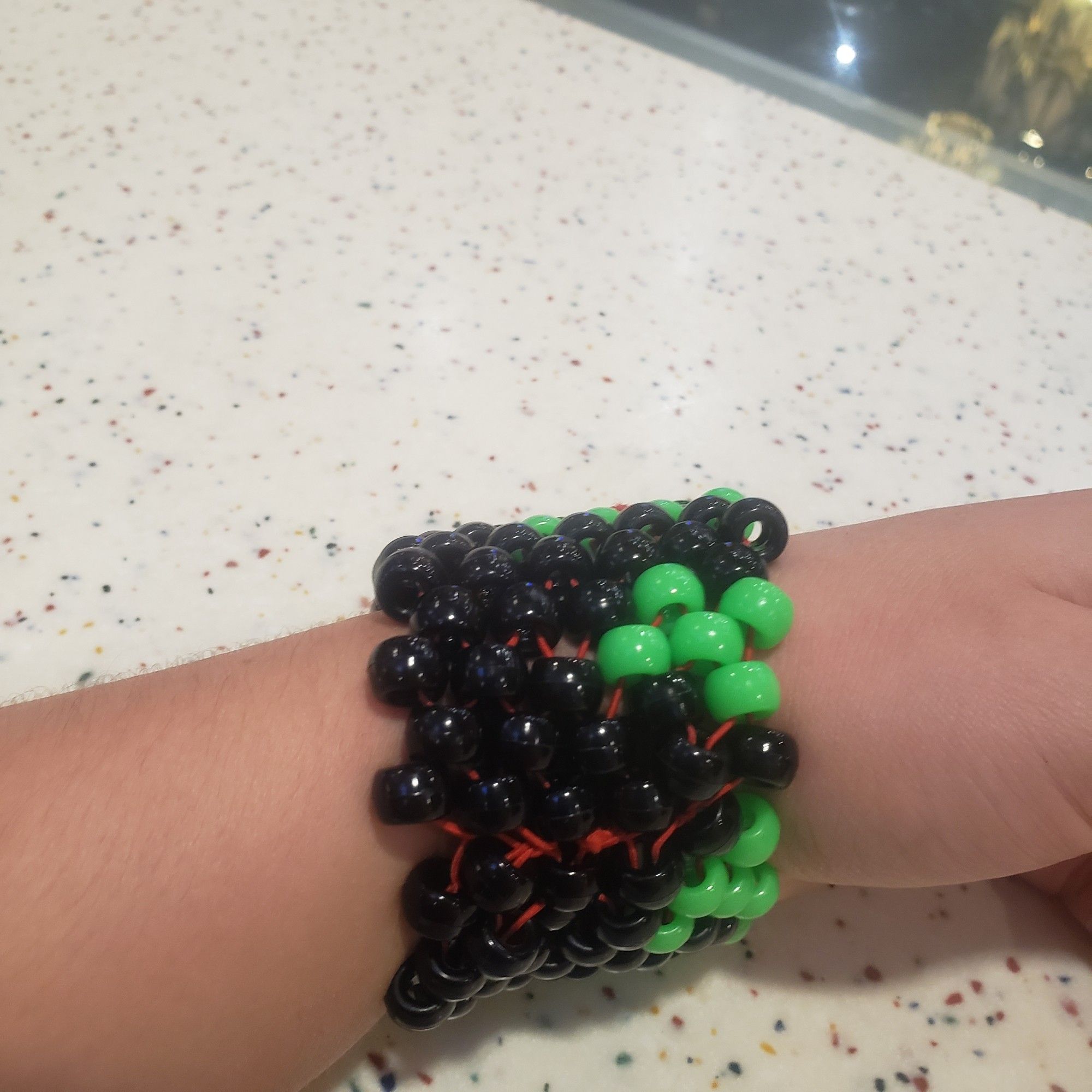 A thick black kandi cuff with green "drips" coming from the top