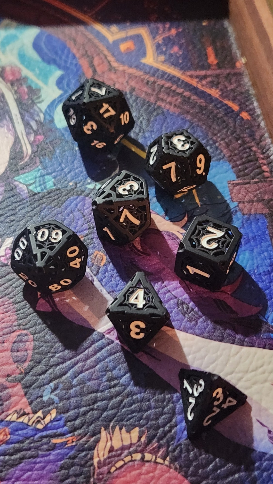 a set of 7 dice, usually used for TTRPG games. These are black metal, with white numbering.