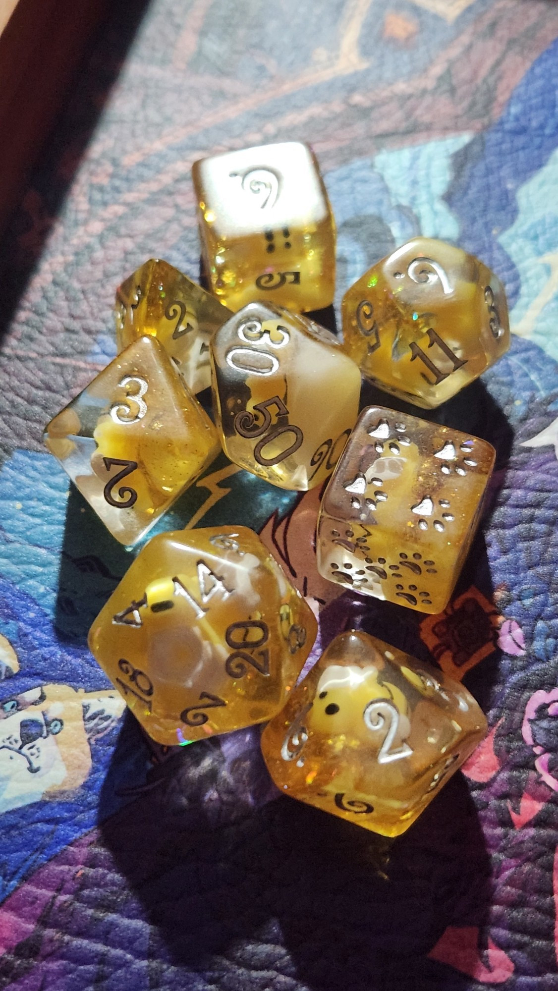 7 set of dice that are yellow and clear, there are little plastic bees in each one. the d6 has paw prints instead of numbers.