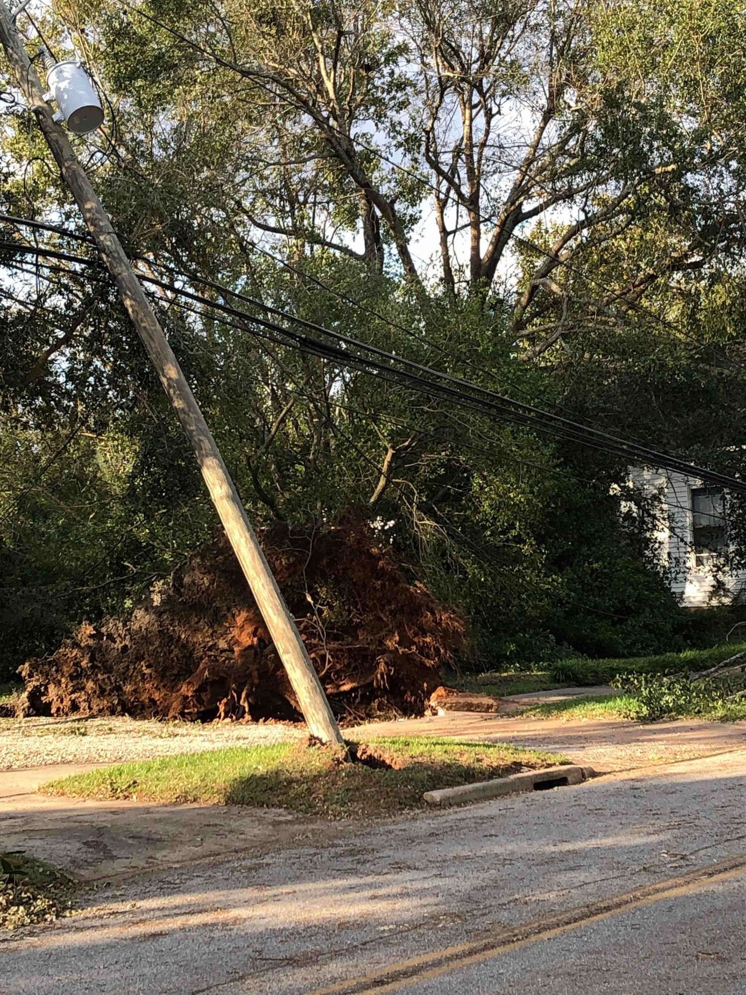 Two power poles lean towards the ground, soon to fall