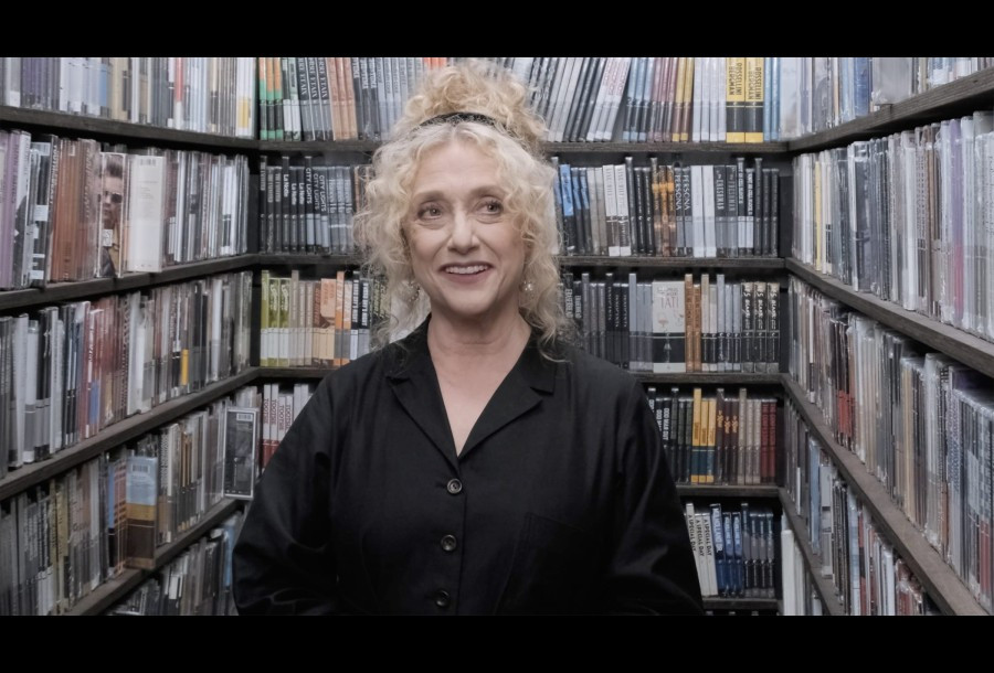 Carol Kane, a white actress with magnificent style, stands in the Criterion Collection Closet, a closet full of Criterion Collection blu-rays.