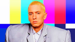 A still of cropped hair white rapper Eminem, against a background of colour blocks. We can't see but he's actually making the deliberately over sized suit David Byrne of Talking Heads wore in the classic movie Stop Making Sense.