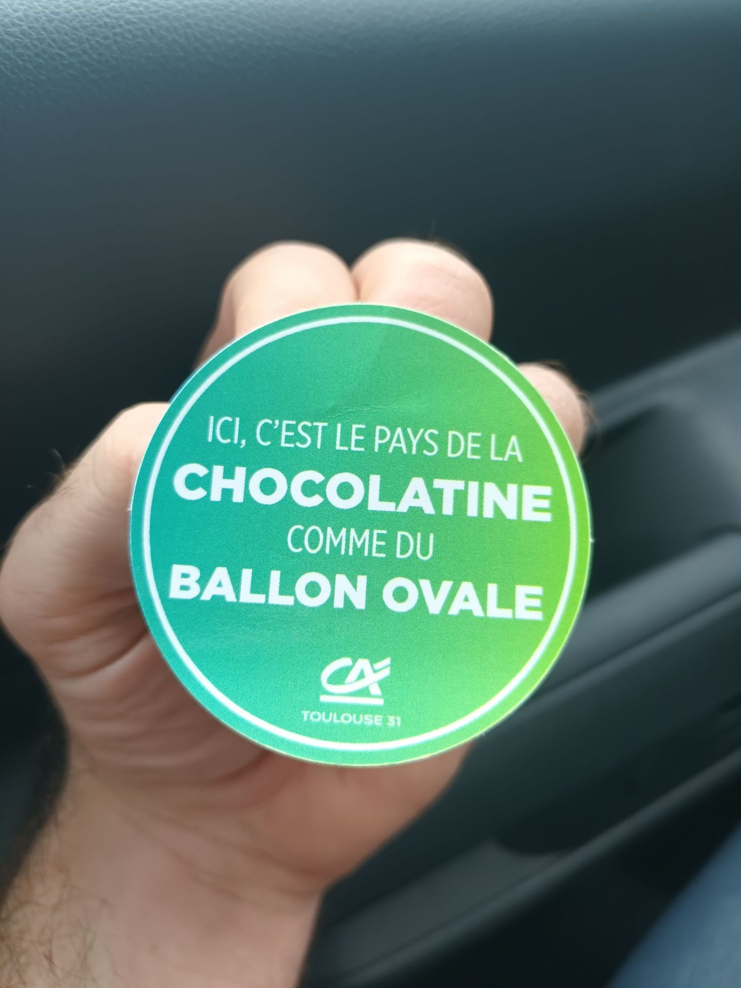 Un pins en plastique de ces sales chiens du crédit agricole ou on peut lire "ici c'est le pays de la chocolatine et du ballon ovale"