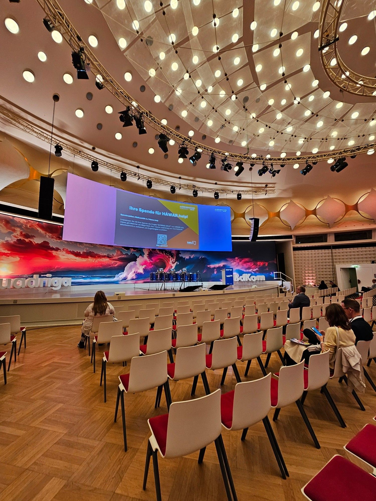 Blick auf die Bühne des Berliner Congress Center, mehrere Stuhlreihen im Vordergrund.