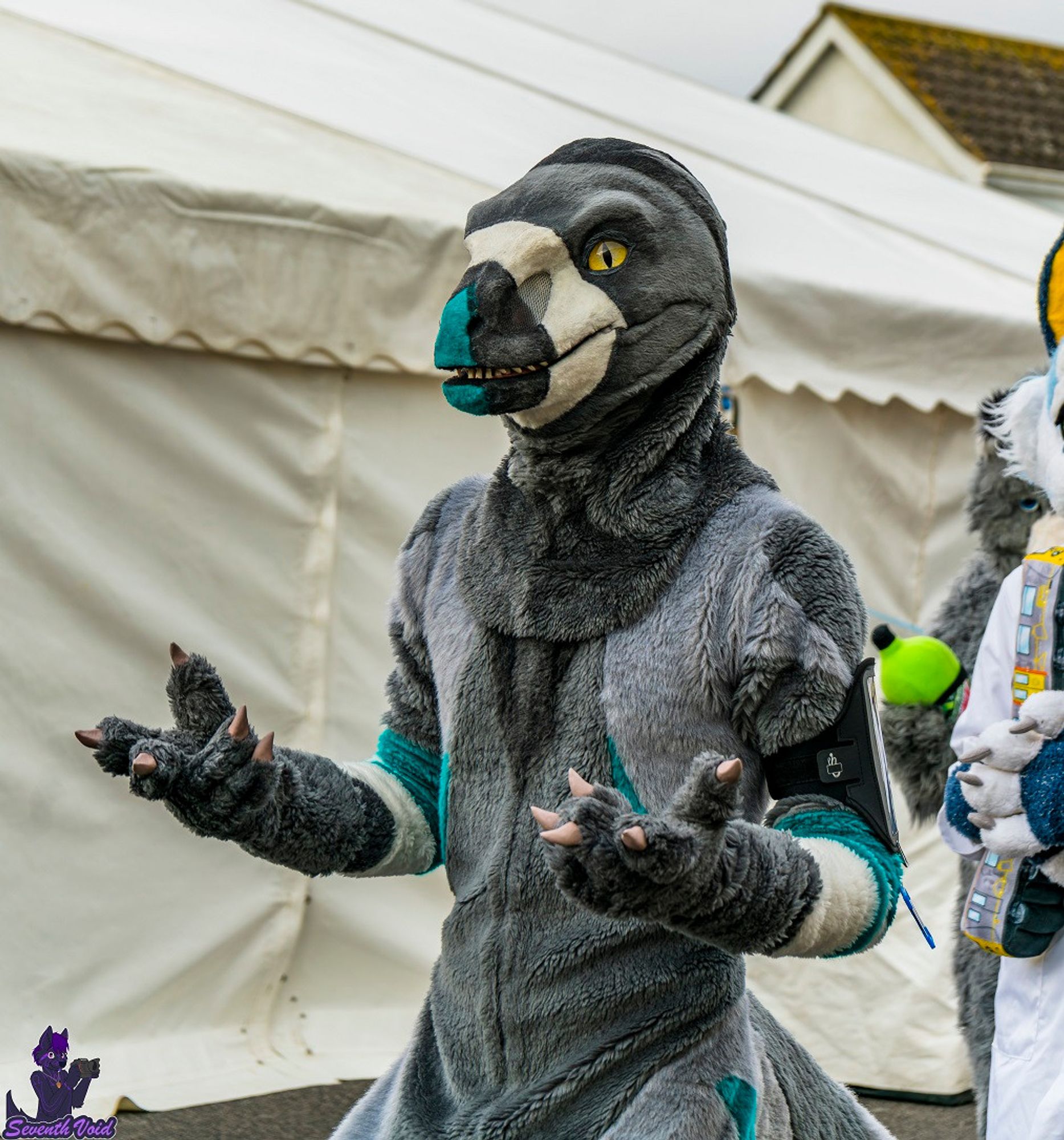 Theta the raptor grinning outside the marquee before the fursuit photoshoot.