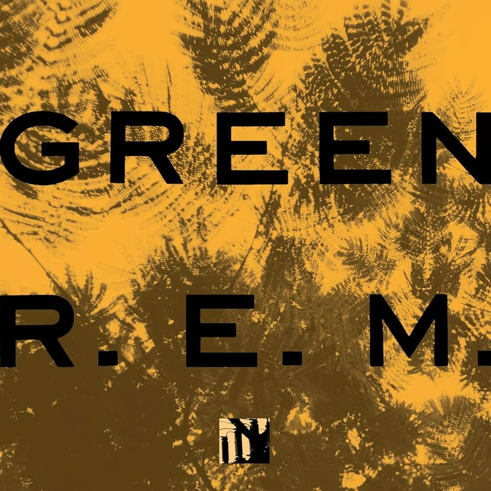 The image shows the album cover for *Green* by *R.E.M.*. The cover features a vibrant, textured background in a yellow-orange tone with dark green fern-like patterns subtly overlaid. The band's name, "R.E.M.," is written in bold black capital letters at the bottom, while the album title, "GREEN," is similarly displayed in large black letters at the top. In the bottom centre of the cover, a small black and white symbol resembling a tree or industrial figure is present, adding a contrasting element to the natural and abstract aesthetic of the background. The overall design is simple yet visually striking.