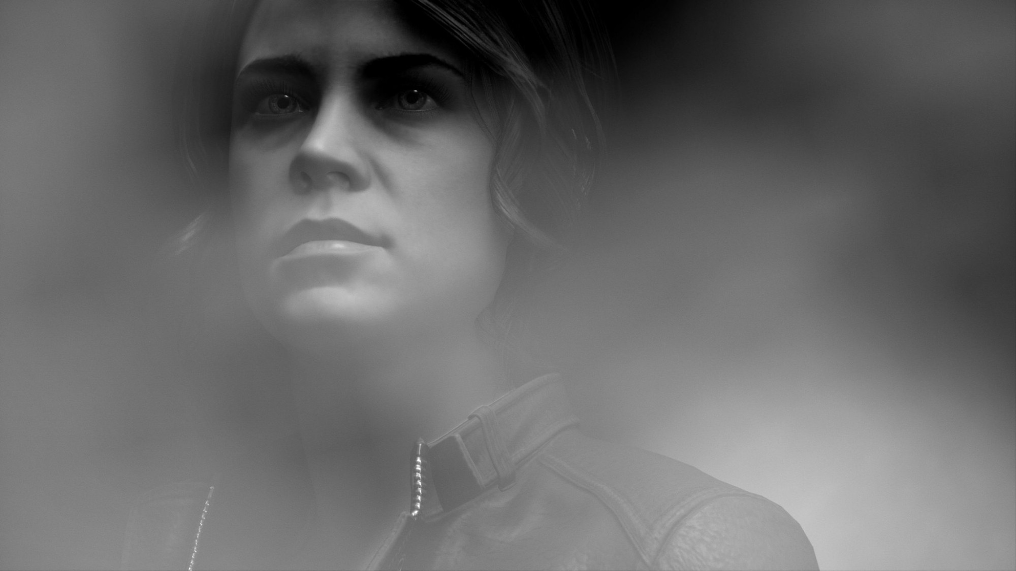 A horizontal black and white portrait of Jesse Faden from the shoulders up. Her eyes, nose, cheekbones and lips are prominently displayed while the rest of her fades out behind gray smoke. She is looking off to the left and up at something out of frame. She has a serene expression. 