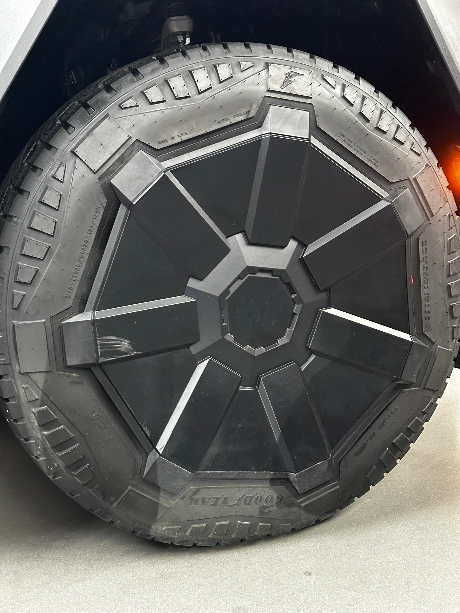 close up of a stock Tesla Cybertruck rim & tire. the tire has custom molding that fits around the shape of the rim.