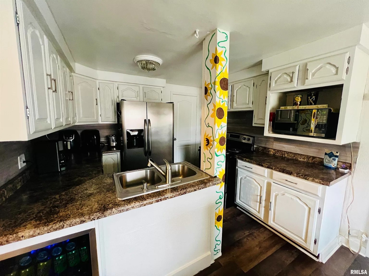 a small kitchen with a large structural post blocking part of the entryway. the post is painted with sunflowers, but it doesn't help