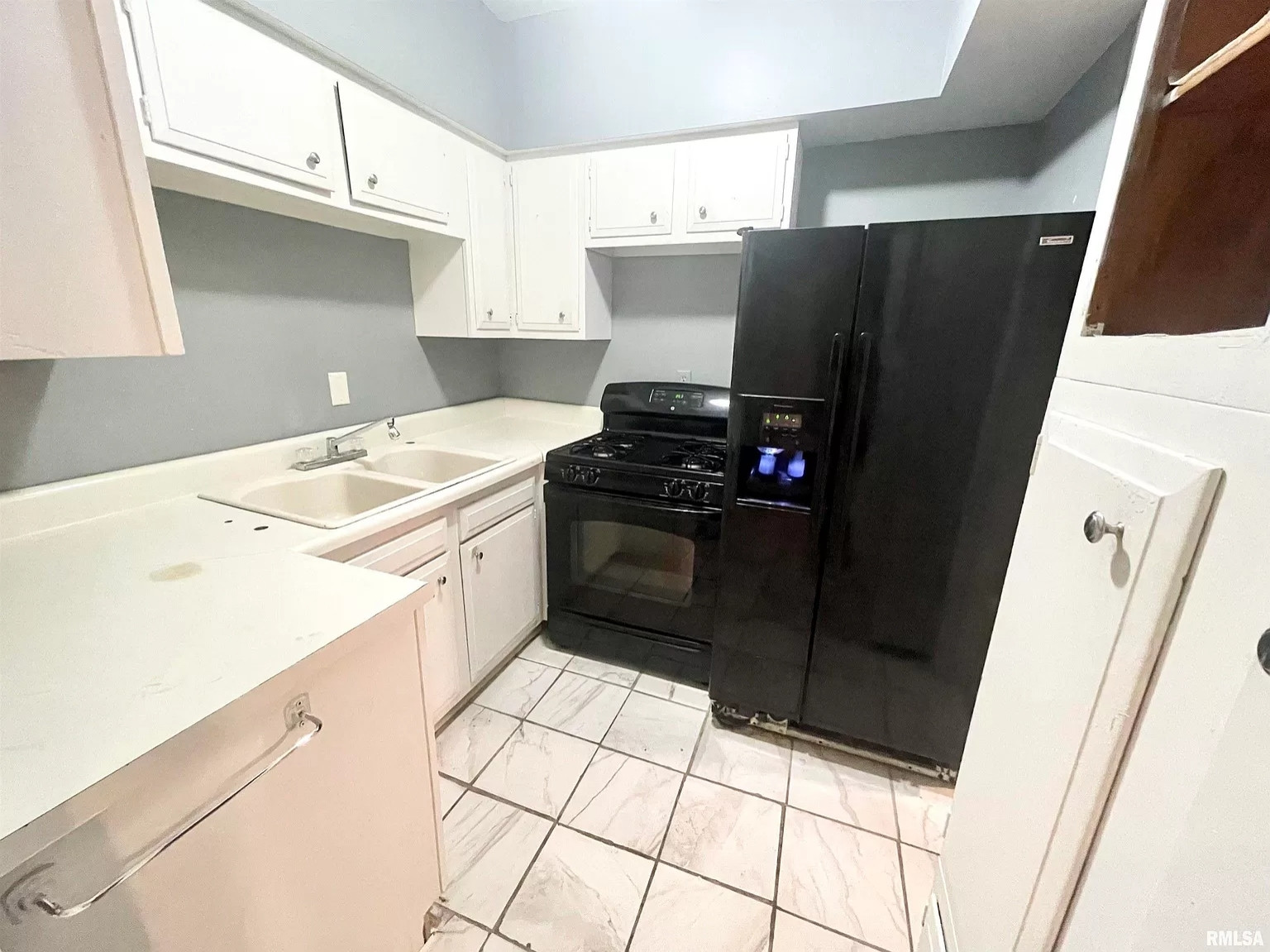 a small kitchen with a relatively reasonable amount of counterspace. but the oven and fridge are jammed up together against the wall at one end of the counter. I doubt the oven opens. also the tilework on the floor is awful, with large square tiles that are not placed square or straight at all.