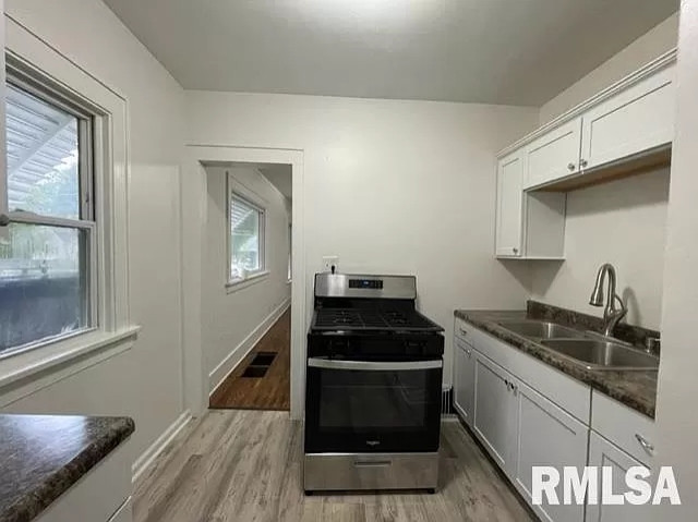 a small kitchen with a gas oven/stove completely blocking an entire span of counterspace, including and drawers