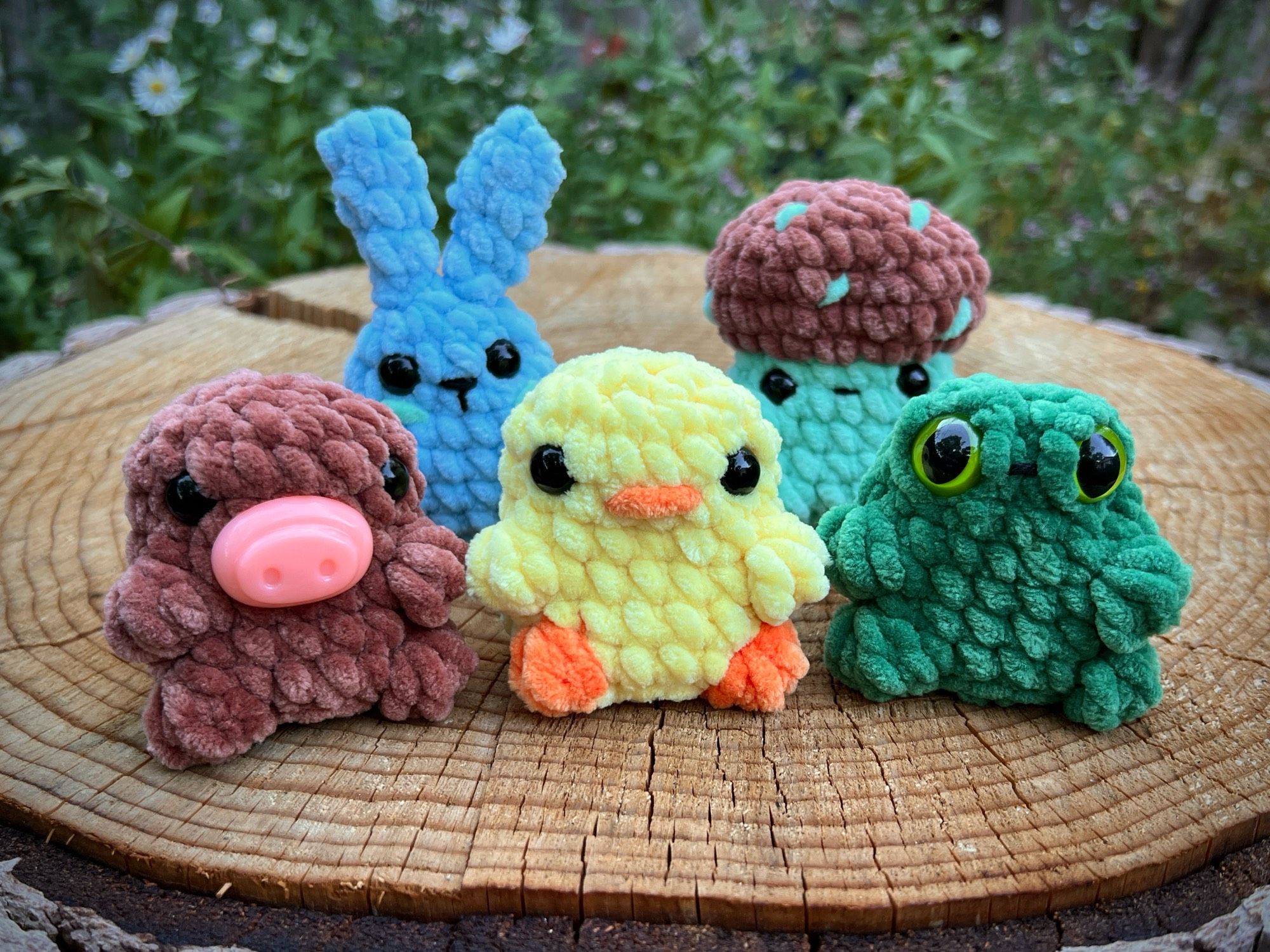 5 mini crochet plush that I’ve made in the last week sitting outside in a stump. A blue bunny, mint chip mushroom, brown pig with no ears yet so it looks like maybe a capybara, yellow chick, and a green frog with big anxiety frog eyes. All so cute!