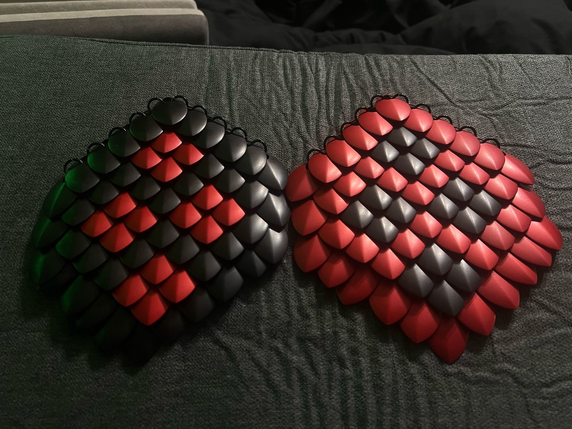 two scale mail “patches”, one black and red, the other red and black, with four harlequin diamonds arranged among the scales on each “patch”