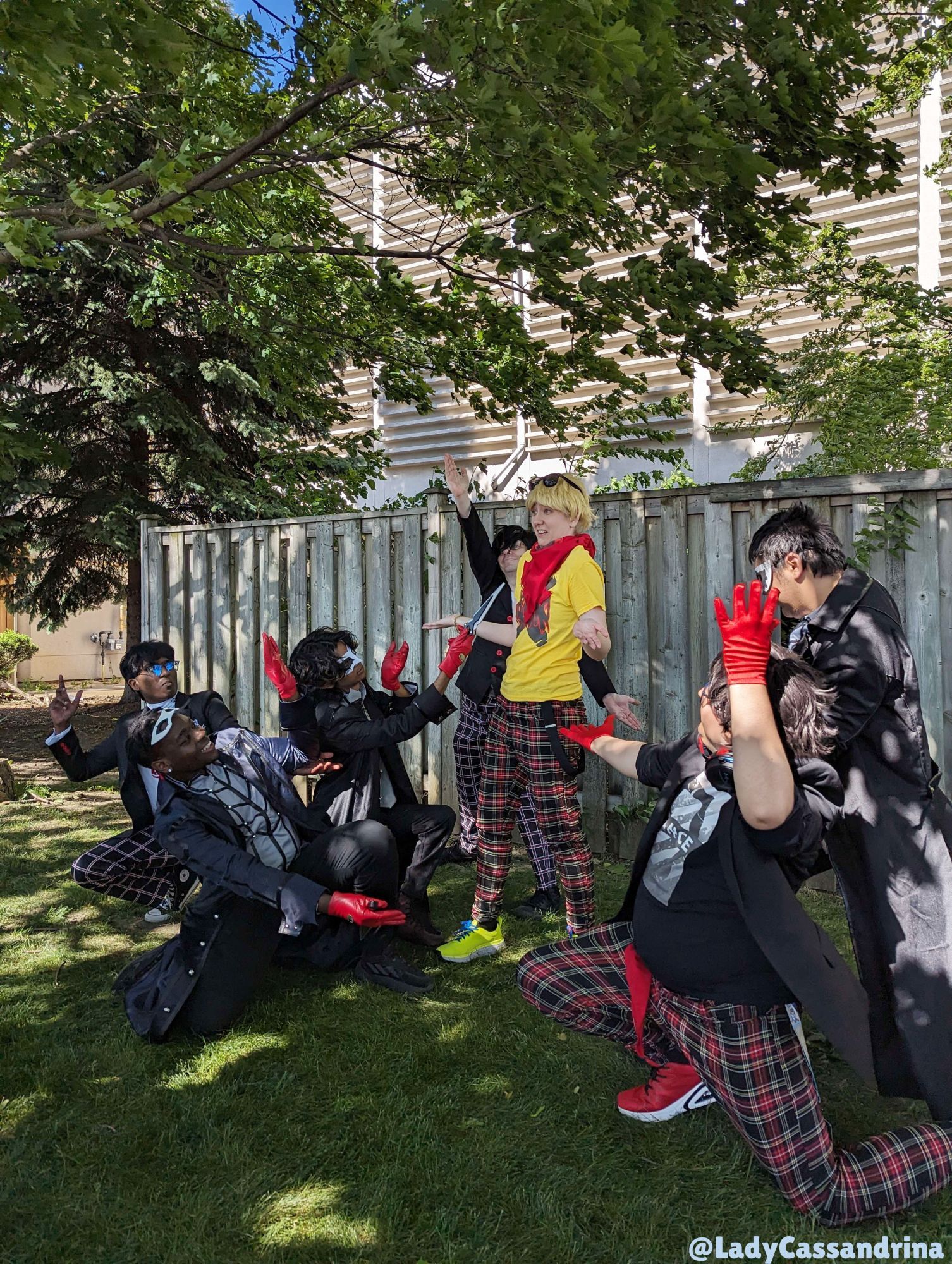 Anime North Persona Cosplay Photoshoot. A group of Jokers surrounds me while I wear my P5 Dancing Ryuji Cosplay. They have their arms gestured at me while I look confused.