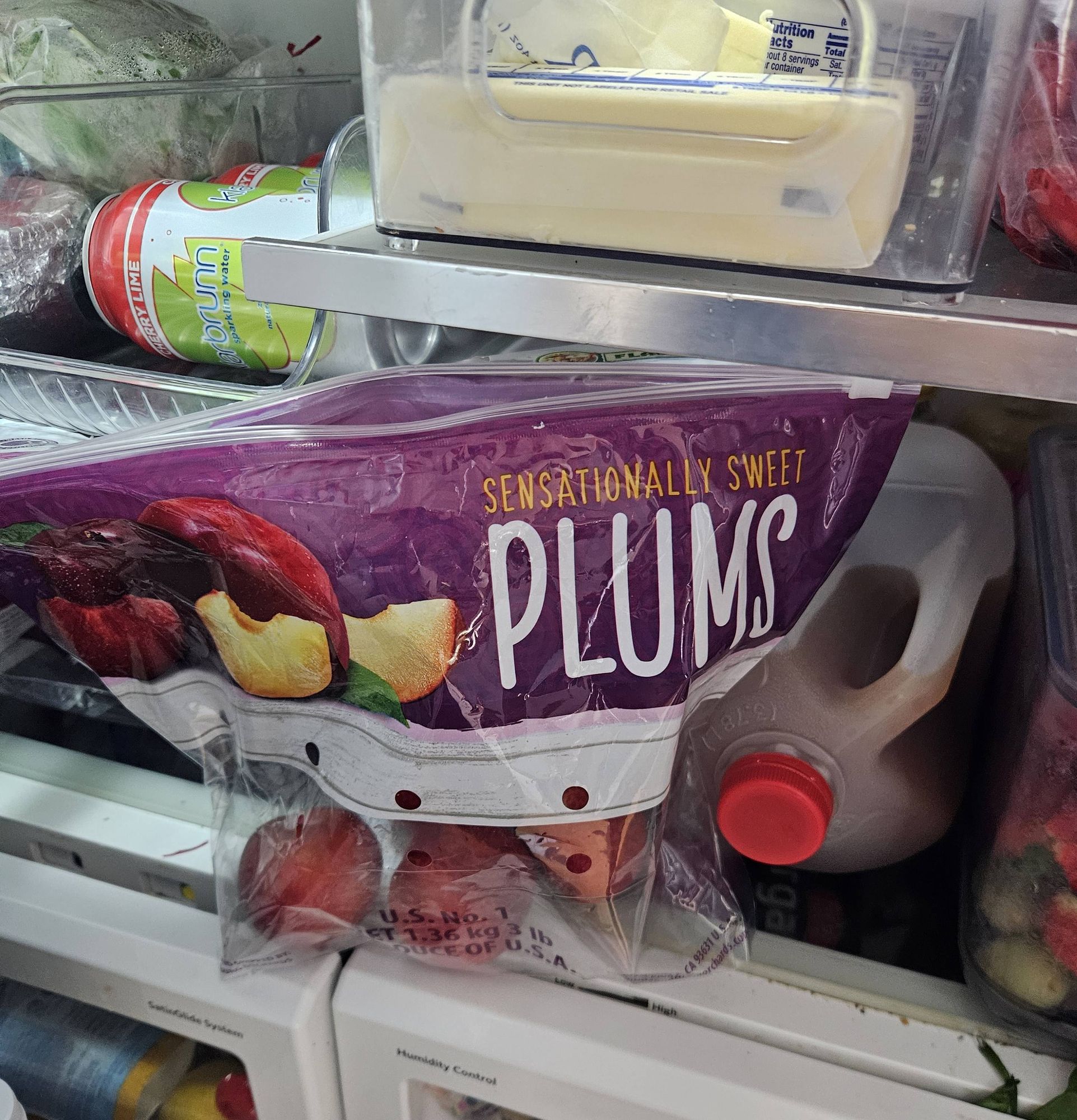 Large bag of plums inside a refrigerator