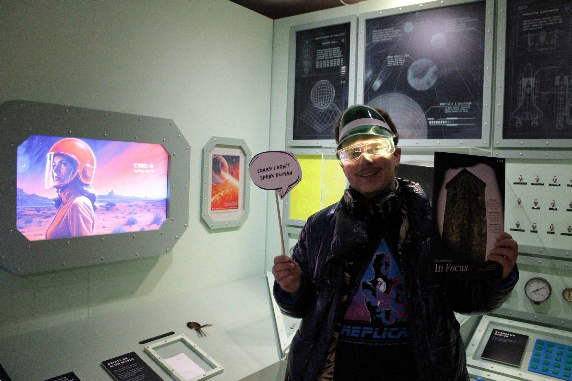 Man in front of a space ship controller, holding a magazine.