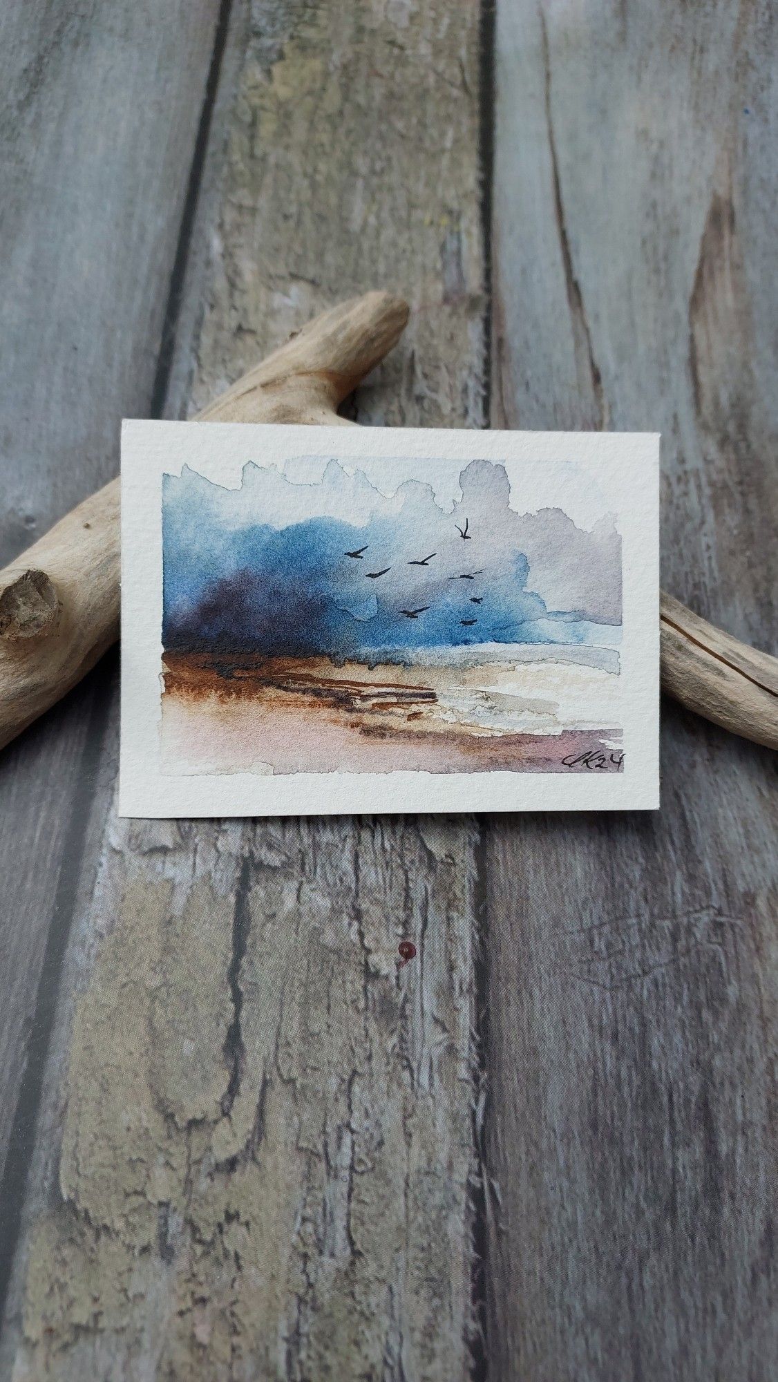 Aquarell mit maritimer oder steinigerLandschaft, abstrakt, lässt Spielraum für Empfingen über den Ort.dunkle Wolken am Himmel, Vögel fliegen.