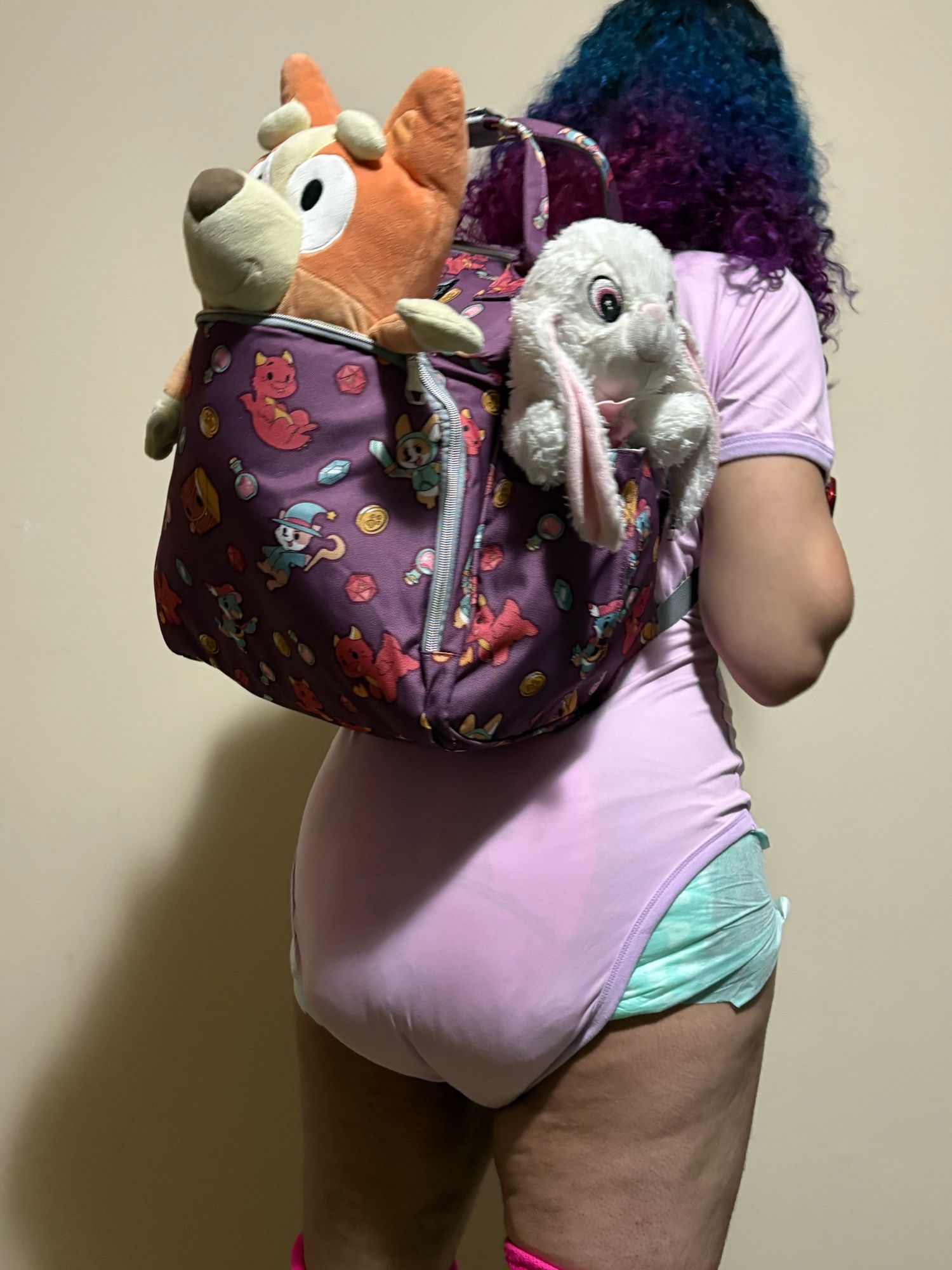 A woman wearing a dungeoneers knapsack , with plushies hanging out the side and back