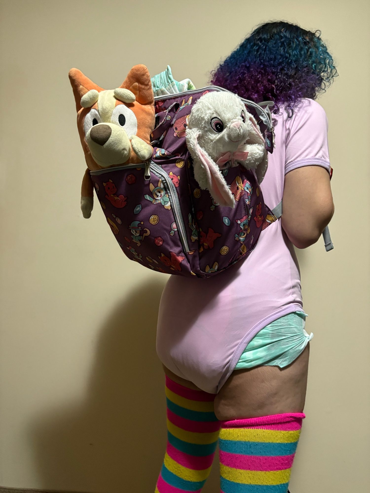 A woman wearing her new dungeoneers knapsack with plushies and a diapee peeking out