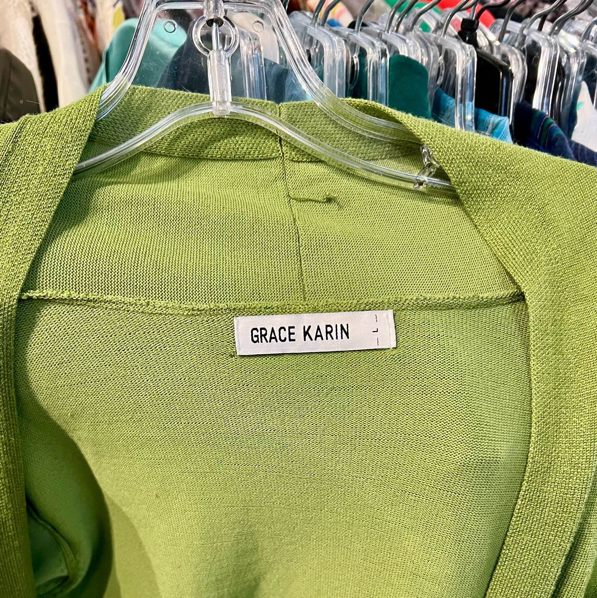 A woman’s sweater on a hanger, with a label stitched “Grace Karin”