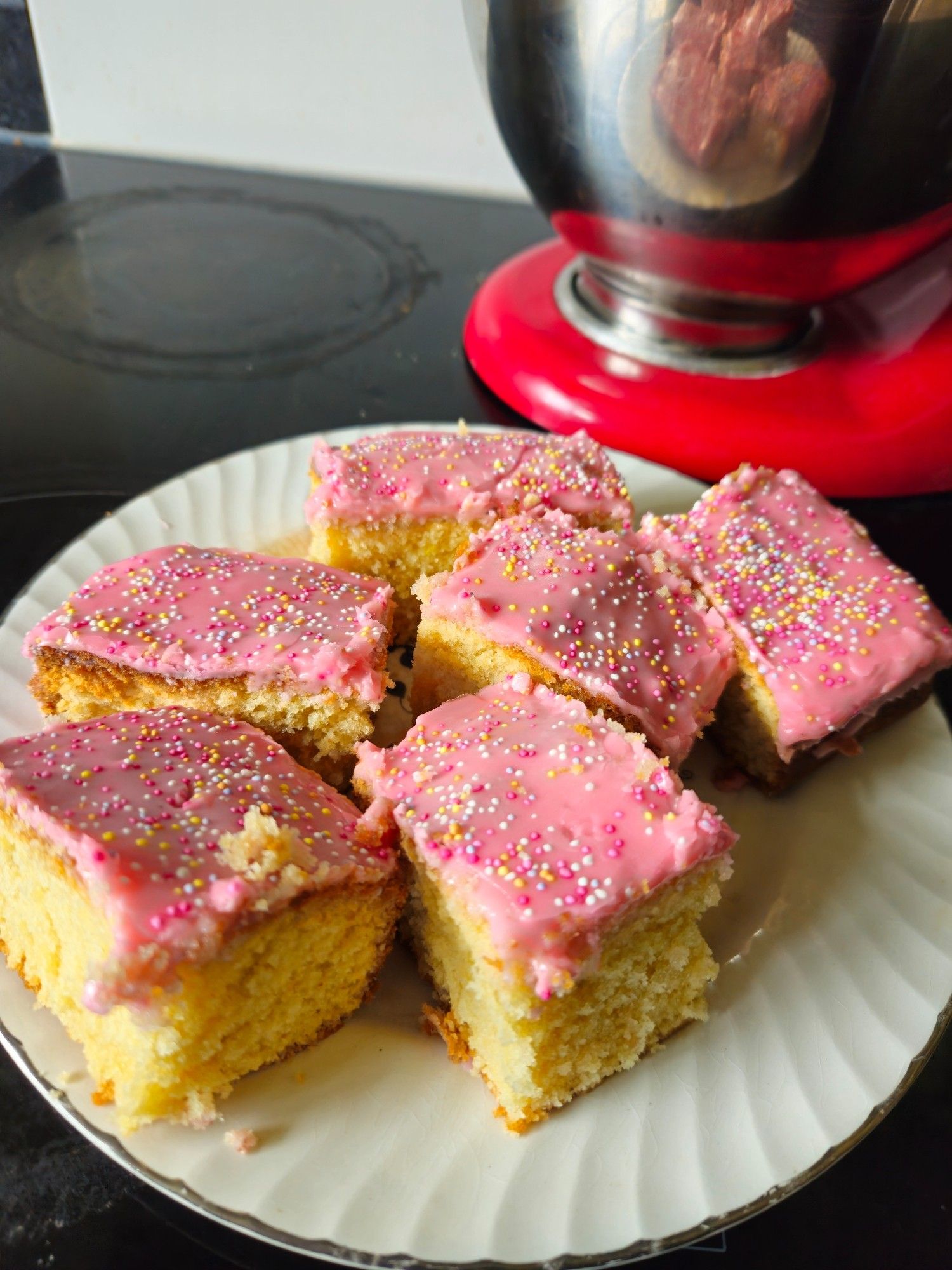 Slices of traditional pink icing topped Tottenham sponge cake, on a plate