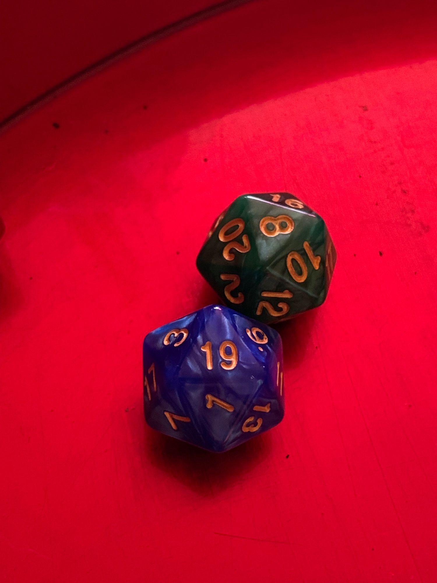 A blue D20 showing 19 and another geeen D20 showing 8 on a red dice tray